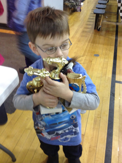 Jackson Woodhead, 4, claims trophies he received during the 2014 Snow Rondi’s pniewood derby. -Photo provided