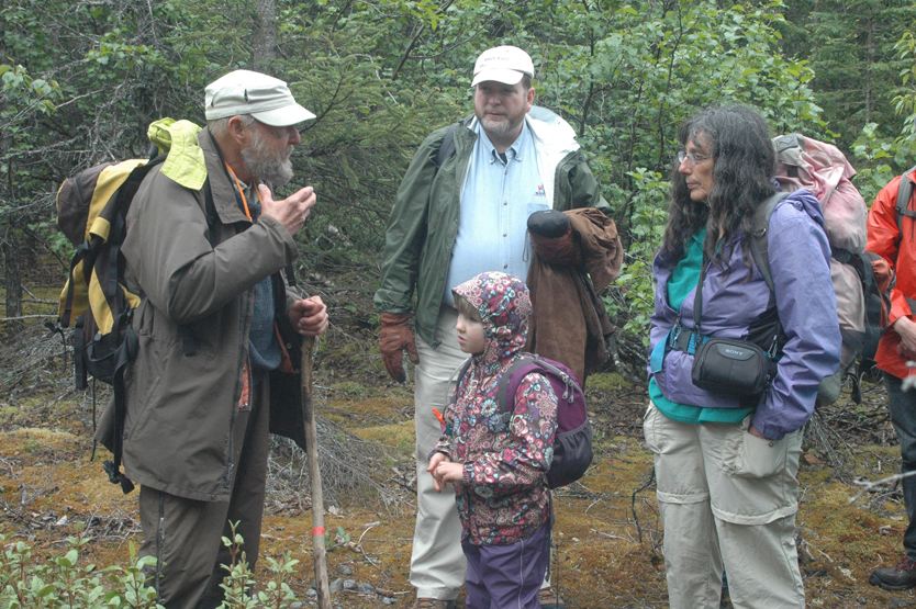 Ed Berg, geology instructor at Kachemak Bay Campus, educates a group of volunteers on the trailside flora during the Trails Day family hike on Saturday. From left are Ed Berg, Phillip Waclawski, Sabre Wilmeth and Carol Sharat.-Photo by Shannon Reid