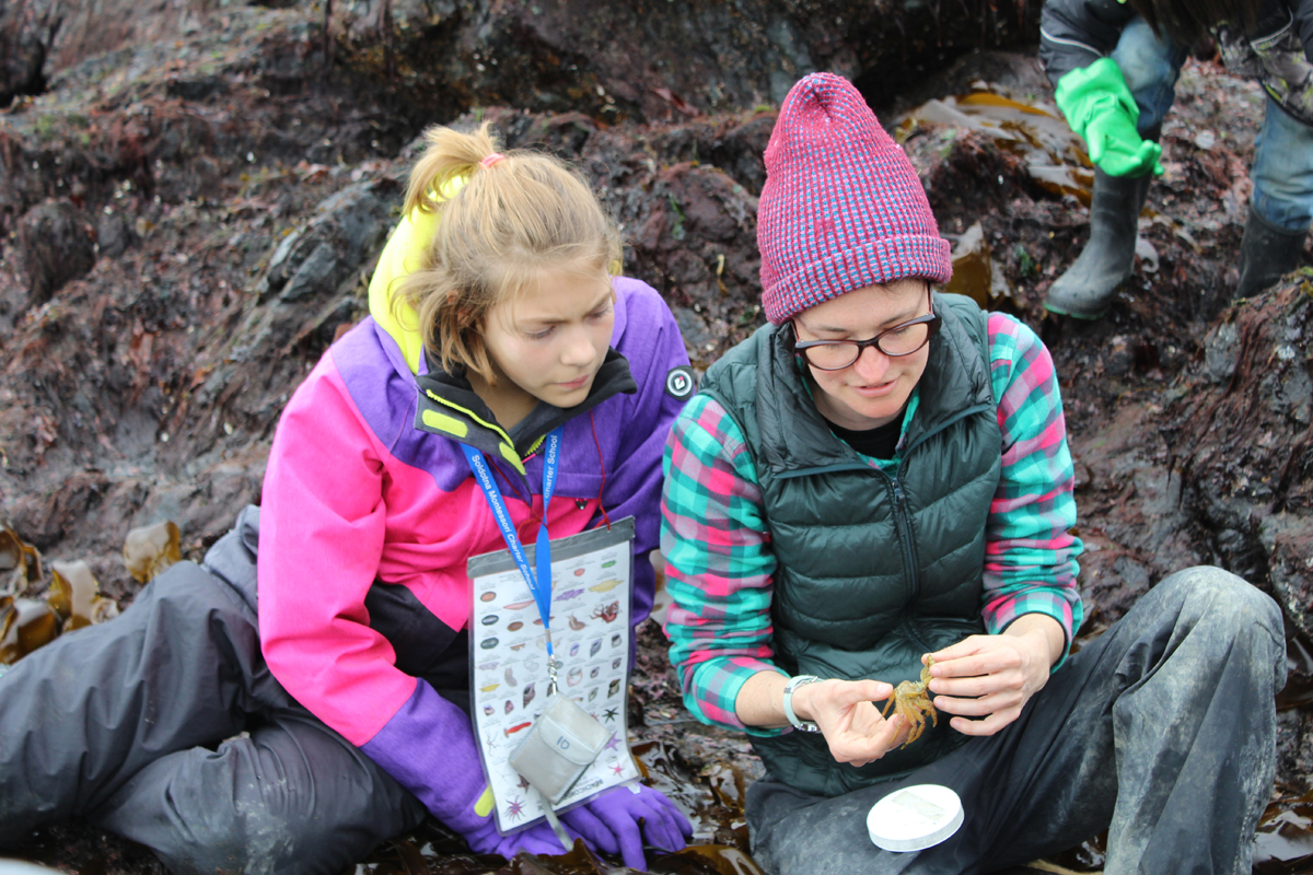 Soldotna Montessori students Kobe Curry and Ella Czarnezki look at a container holding a tiny organism found by one of the Peterson Bay Field Station naturalists during their exploration of Otter Rock. -Photo by Anna Frost; Homer News