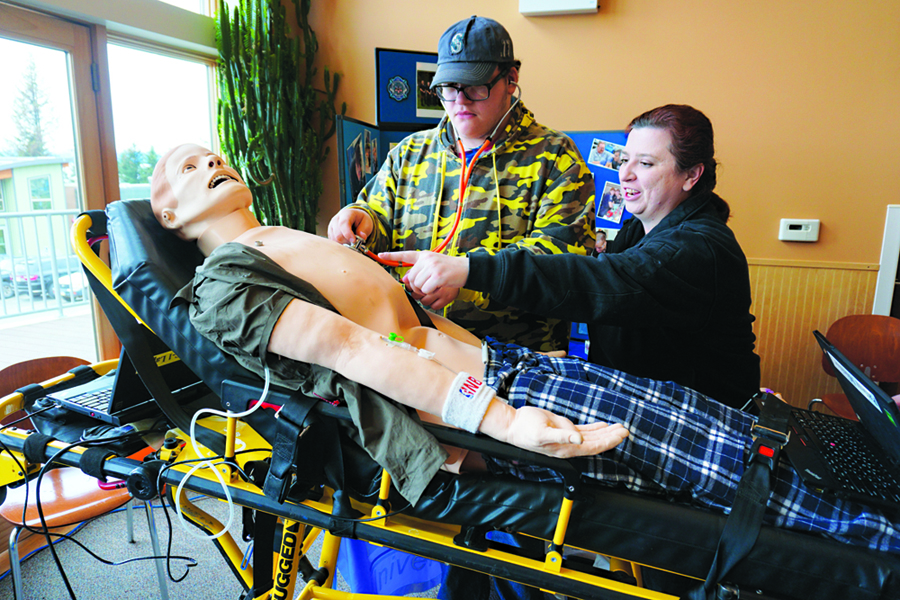 Amanda Dorough, right, shows Homer High School senior Griffin Scero how to listen to breathing in Sim Man, a robotic teaching mannequin, at the Homer College, Career and Job Fair last Friday at Kachemak Bay Campus. Dorough is a student in the paramedic program at the Kenai Peninsula College, Kenai River Campus. The $125,000 teaching tool can simulate thousands of medical situations, including heart attacks.                               -A full recovery is expected