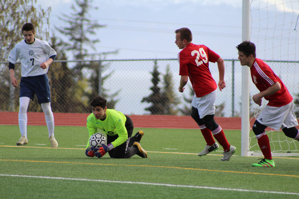 Homer goalie Kenzington Cortez snatches up the ball to prevent a Kenai goal attempt during the Tuesday, April 26 home game. -Photo by Anna Frost; Homer News