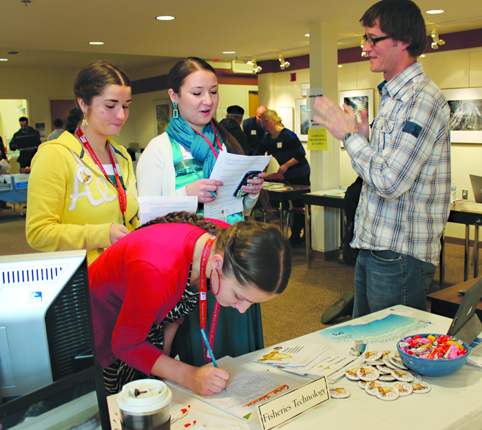Project GRAD students from Kachemak Selo — from left, Ksenia Reutov, Mariania Reutov and Katherine Konev — check out he University of Alaska Southeast’s fisheries technology program at the 2014 Homer Career, College and Job Fair at the Kachemak Bay Campus.