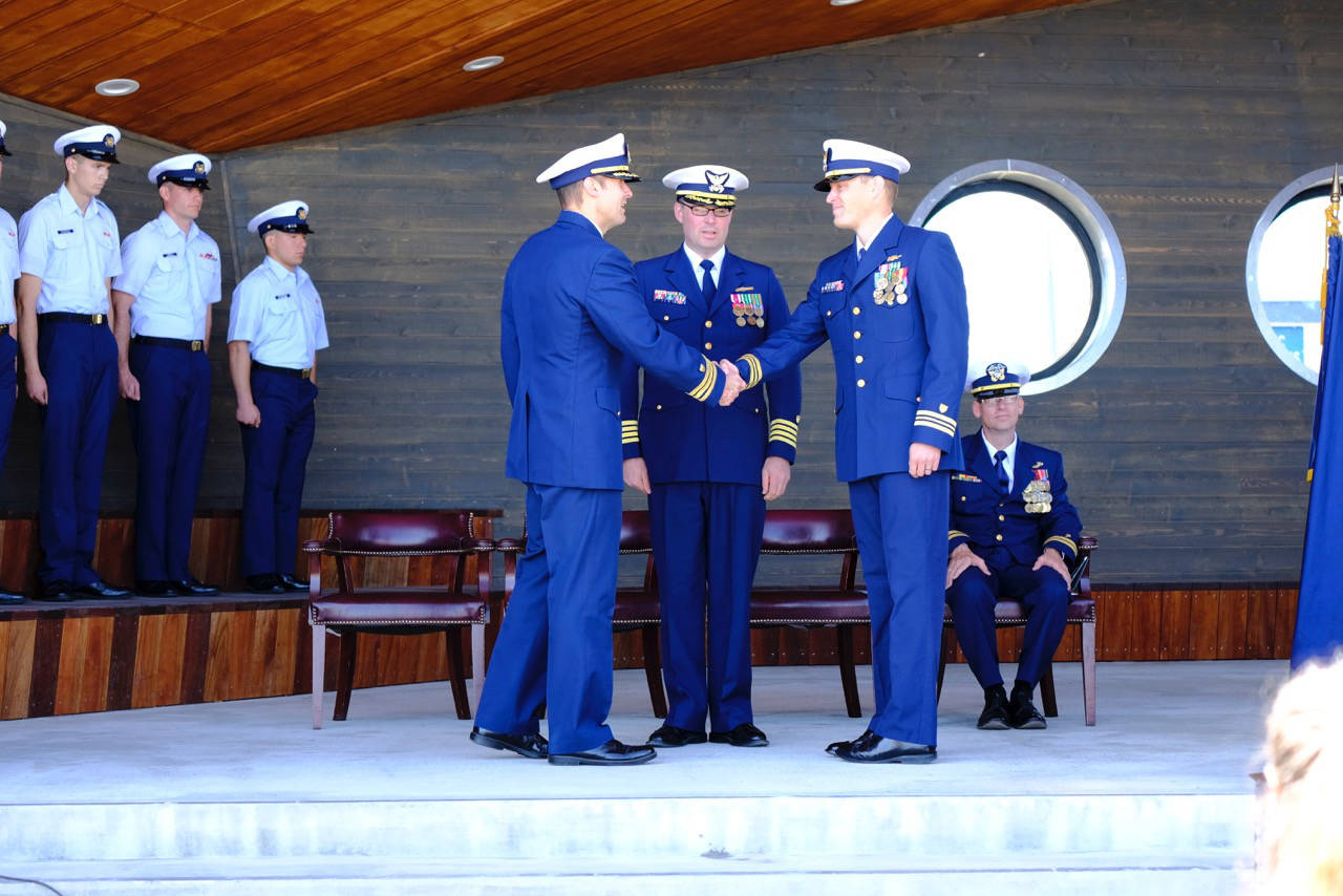At a change of command ceremony on July 18, 2018 command of the USCGC Hickory is handed from Commander Andrew Passic (left) to Lt. Commander Adam Legget (second to right) at the Homer Boat House in Homer, Alaska. Overseeing the change of command is Capt. Patrick Hilbert (second to left) and Chaplain Lt. Gary Pepper (right). The ceremony took place in the new Homer Boat House at the Homer Harbor. (Photo by PO2 Andrew Keenan, Marine Safety Detachment Homer, United States Coast Guard)