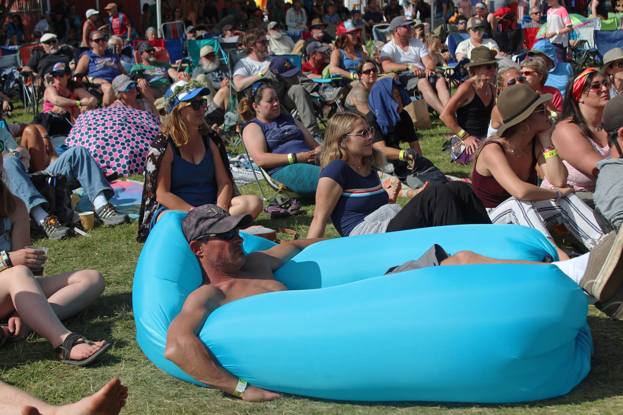 A festival goer reclines in the grass while watching a performance at the Ocean Stage on Saturday, Aug. 4, 2018 at Salmonfest in Ninilchik, Alaska. (Photo by Megan Pacer/Homer News)