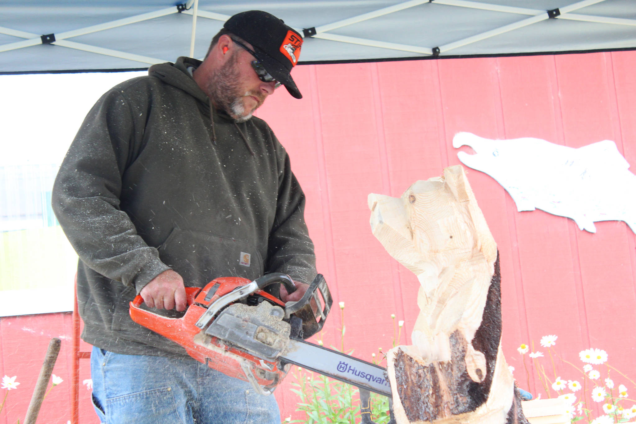 Guy Lane carves a bear statue while onlookers watch Friday, Aug. 18, 2017 at the Kenai Peninsula Fair in Ninilchik, Alaska. Lane works at Alaska Bear Factory LLC, owned by Kim Sangder, which just moved down from Sterling to Homer. (Photo by Megan Pacer/Homer News)