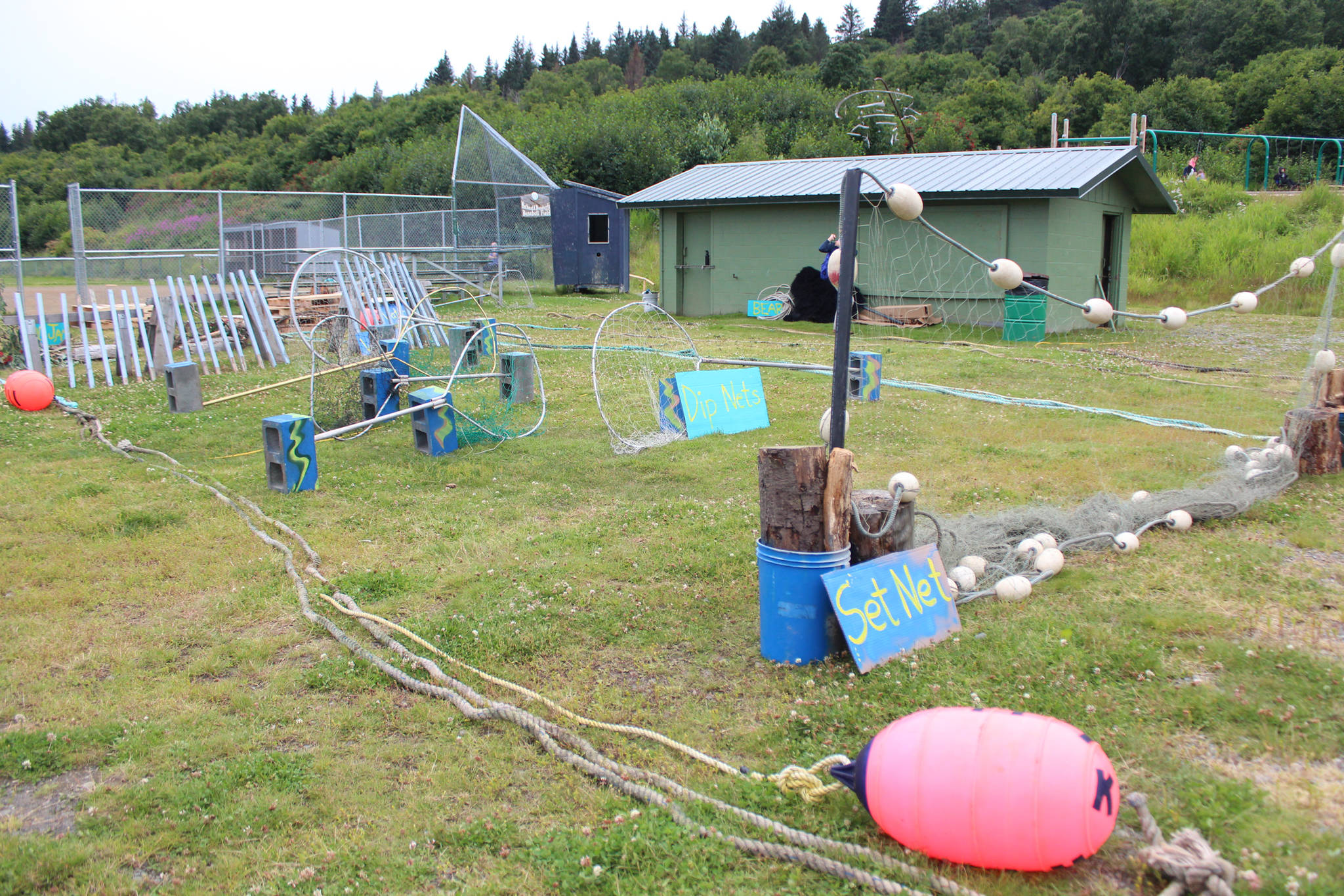 Signs identify the different stages of an obstacle course set up in Karen Hornaday Park for Alaska Wild Salmon Day on Friday, Aug. 10, 2018 in Homer, Alaska. Kids had to think like salmon to get through the set nets, dipnets, the weir, and other obstacles. (Photo by Megan Pacer/Homer News)