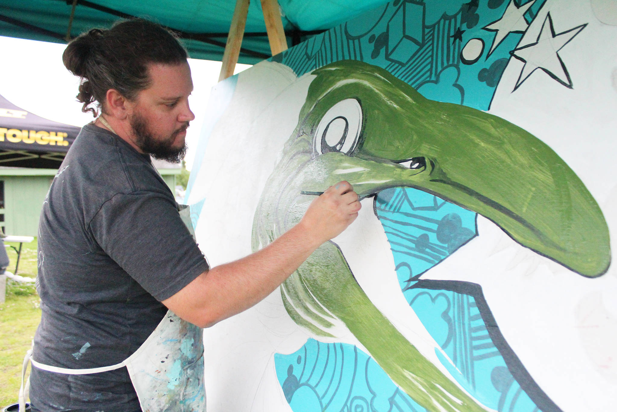 Colorado artist Patrick Maxcy works on a painting of a salmon during a public barbecue at Karen Hornaday Park for Alaska Wild Salmon Day on Friday, Aug. 10, 2018 in Homer, Alaska. Cook Inletkeeper has partnered with The Bunnell Street Arts Center to host Maxcy as artist in residence for August. (Photo by Megan Pacer/Homer News)