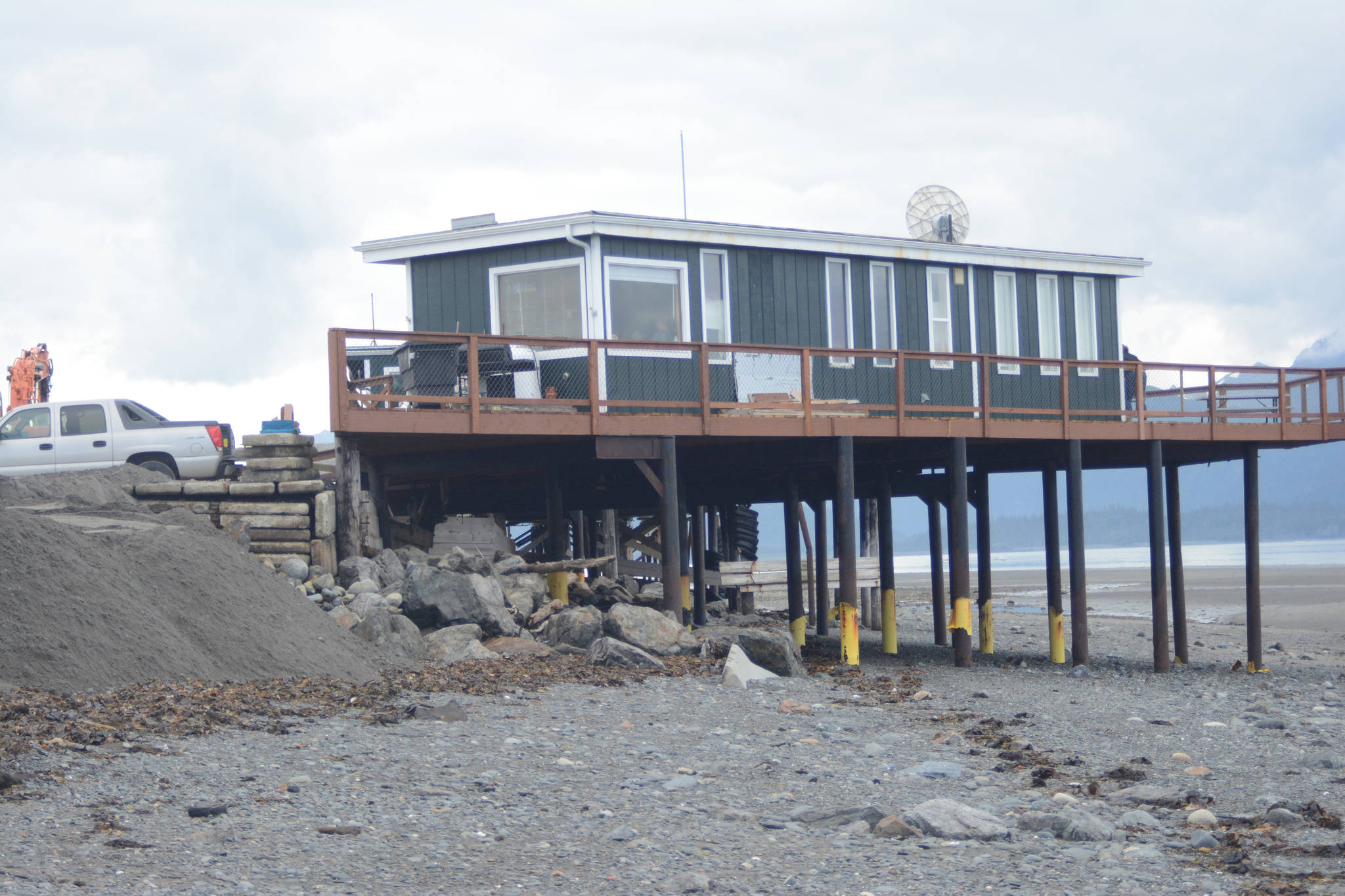 Fresh fill added on Aug. 15, 2018, replaces sand washed away last week after a series of storms and high tides eroded the beach near the Glacier Drive-In restaurant, shown here Aug. 16, 2018, on the Homer Spit, Alaska. Concrete armor rock holds the parking lot in place. The yellow plastic on the steel pilings shows where sand had been when they were installed several years ago. (Photo by Michael Armstrong/Homer News)