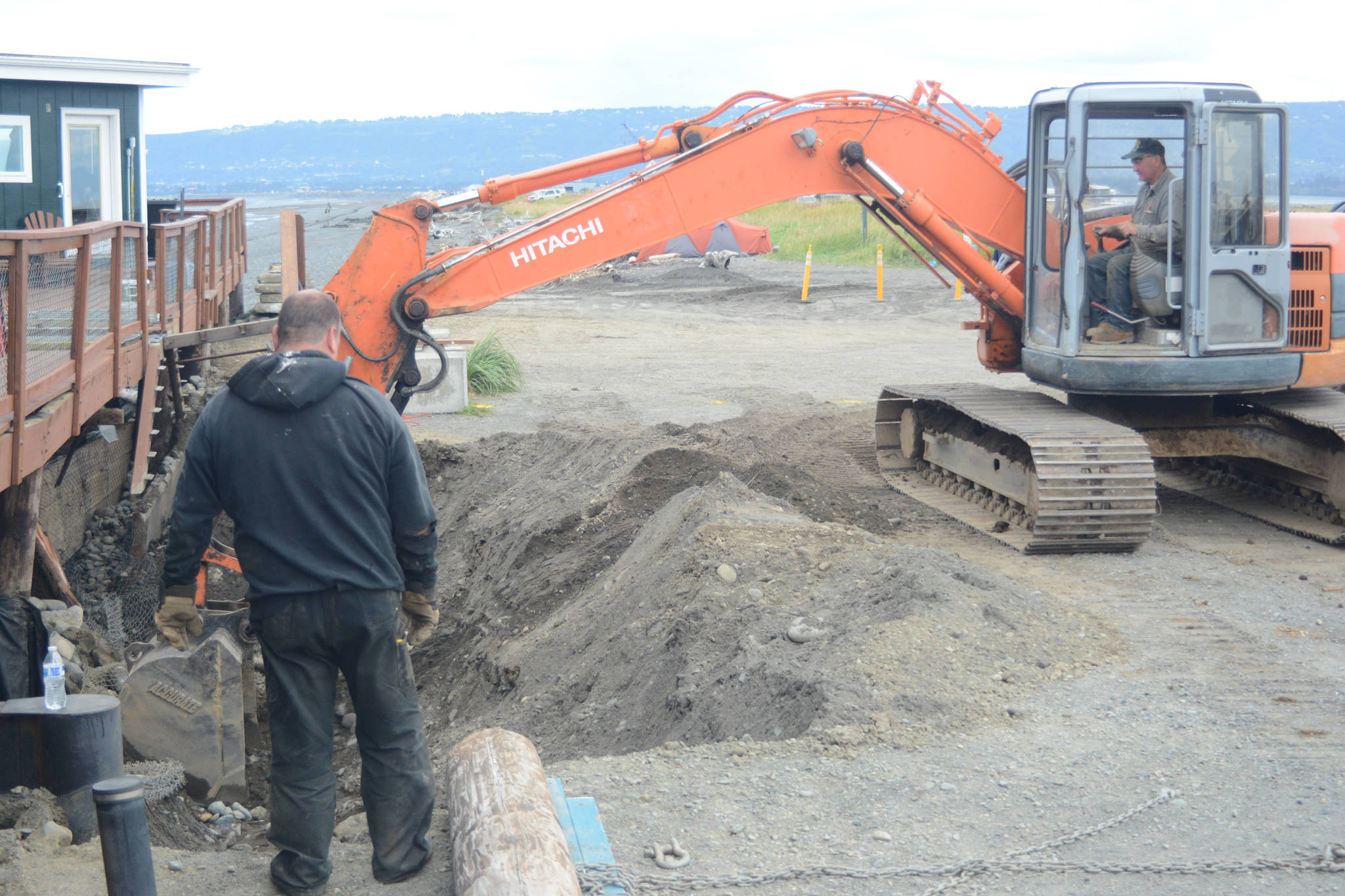 John Wise, left, and Nathan Wise, right, in backhoe, make repairs of the Glacier Drive-In on the Homer Spit, on Aug. 16, 2018, after a series of storms that eroded the beach last week during high tides in Homer, Alaska. (Photo by Michael Armstrong/Homer News)