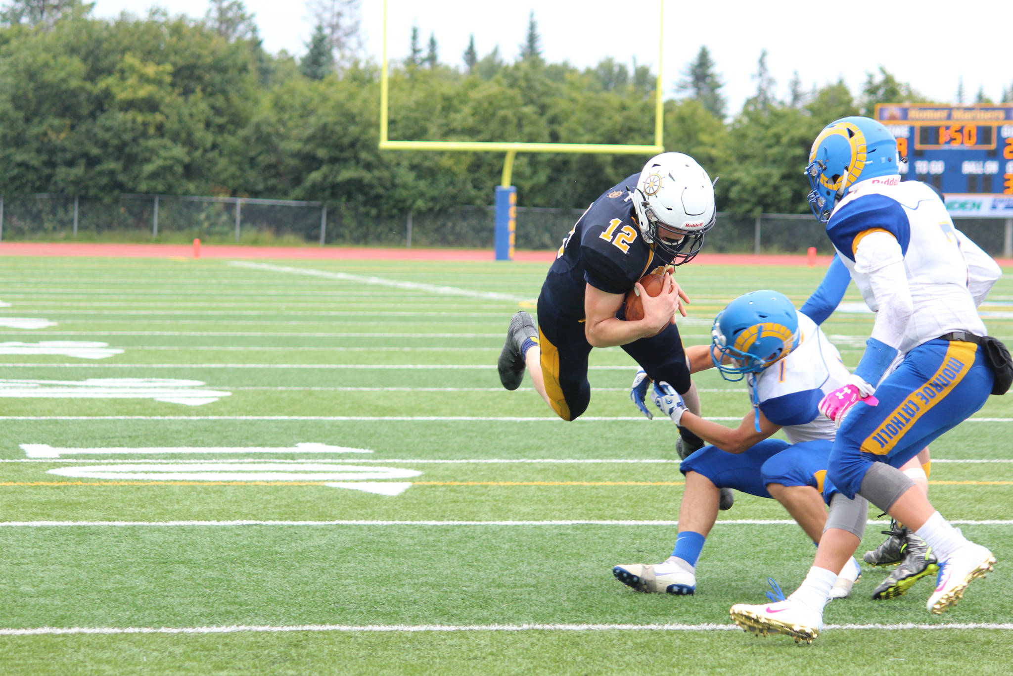 Quarterback Anthony Kalugin runs the ball while being tackled by Monroe Catholic High School’s Jordan Higbee during their game Saturday, Aug. 25, 2018 at Homer High School in Homer, Alaska. The Rams beat the Mariners in a close game 28-27. (Photo by Megan Pacer/Homer News)