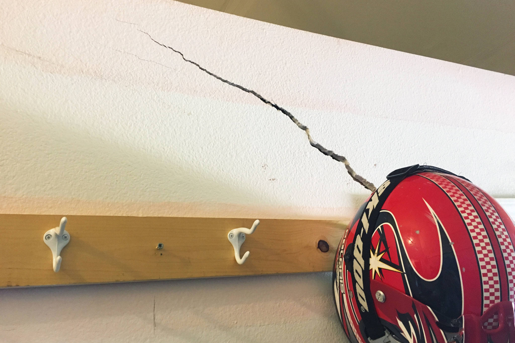A crack rises up the wall near a coat hanger Thursday, Aug. 30, 2018 in the middle-high school building at Kachemak Selo School in the village at the head of Kachemak Bay, Alaska. The three buildings that make up the school facility have been experiencing structural and other issues for years. (Photo by Megan Pacer/Homer News)