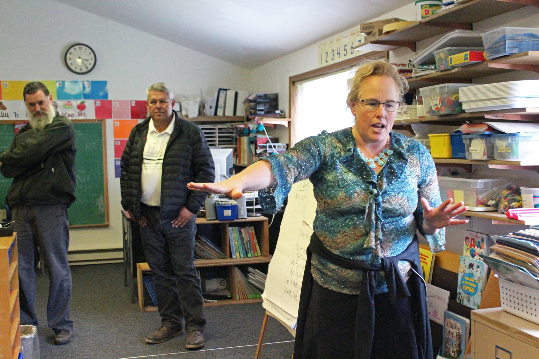 Alana Greear, an elementary school teacher at Kachemak Selo School, shows visitors from the Kenai Peninsula Borough and school district where one of the two elementary buildings has experienced flooding over the years during a visit Thursday, Aug. 30, 2018 in Kachemak Selo, Alaska. The building Greear teaches in also has a wall that lifts up and separates from the floor during winter. (Photo by Megan Pacer/Homer News)