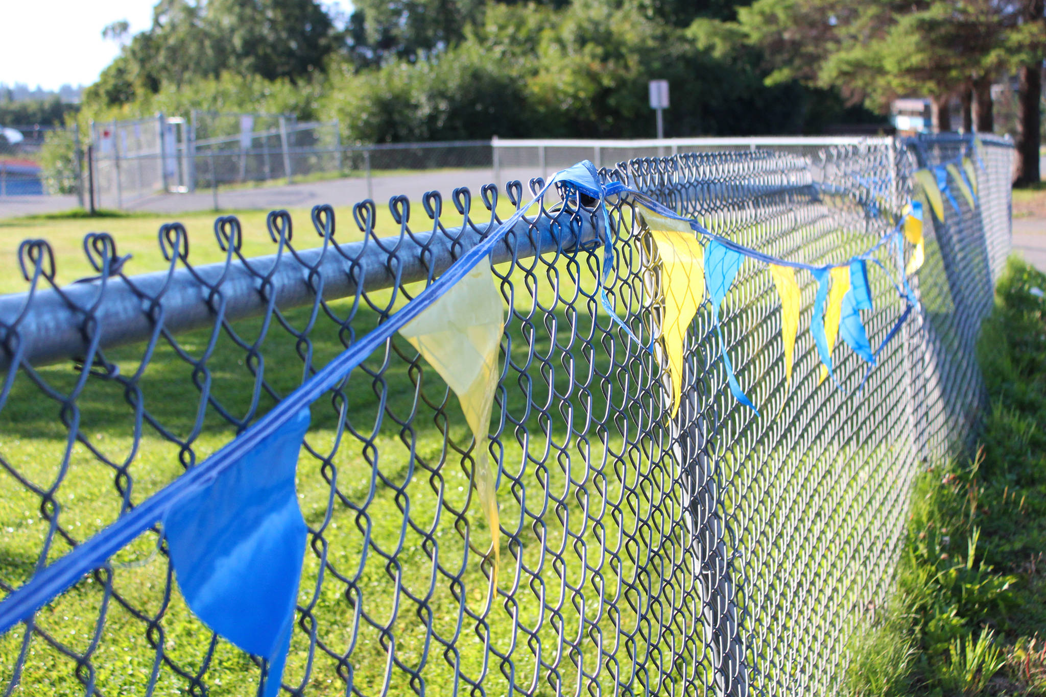 Flags decorate a fence near the finish line of the Homer Mariner Triathlon on Saturday, Sept. 1, 2018 at Homer High School in Homer, Alaska. (Photo by Megan Pacer/Homer News)