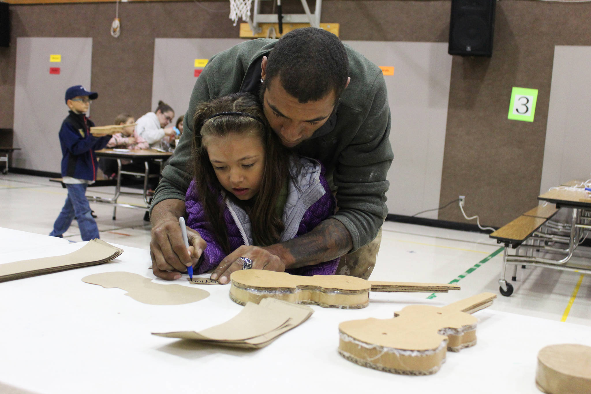 Alonzo Lang helps his 5-year-old daughter, Payton, create a violin out of cardboard during a craft night at Paul Bank Elementary School on Thursday, Sept. 6, 2018 at the school in Homer, Alaska. The project is part of the school’s Preludes Violin Program, which teaches first and second grade students musicianship and the host of skills that come with it. Students start out with the cardboard violins before graduating to the real instruments later in the year. (Photo by Megan Pacer/Homer News)