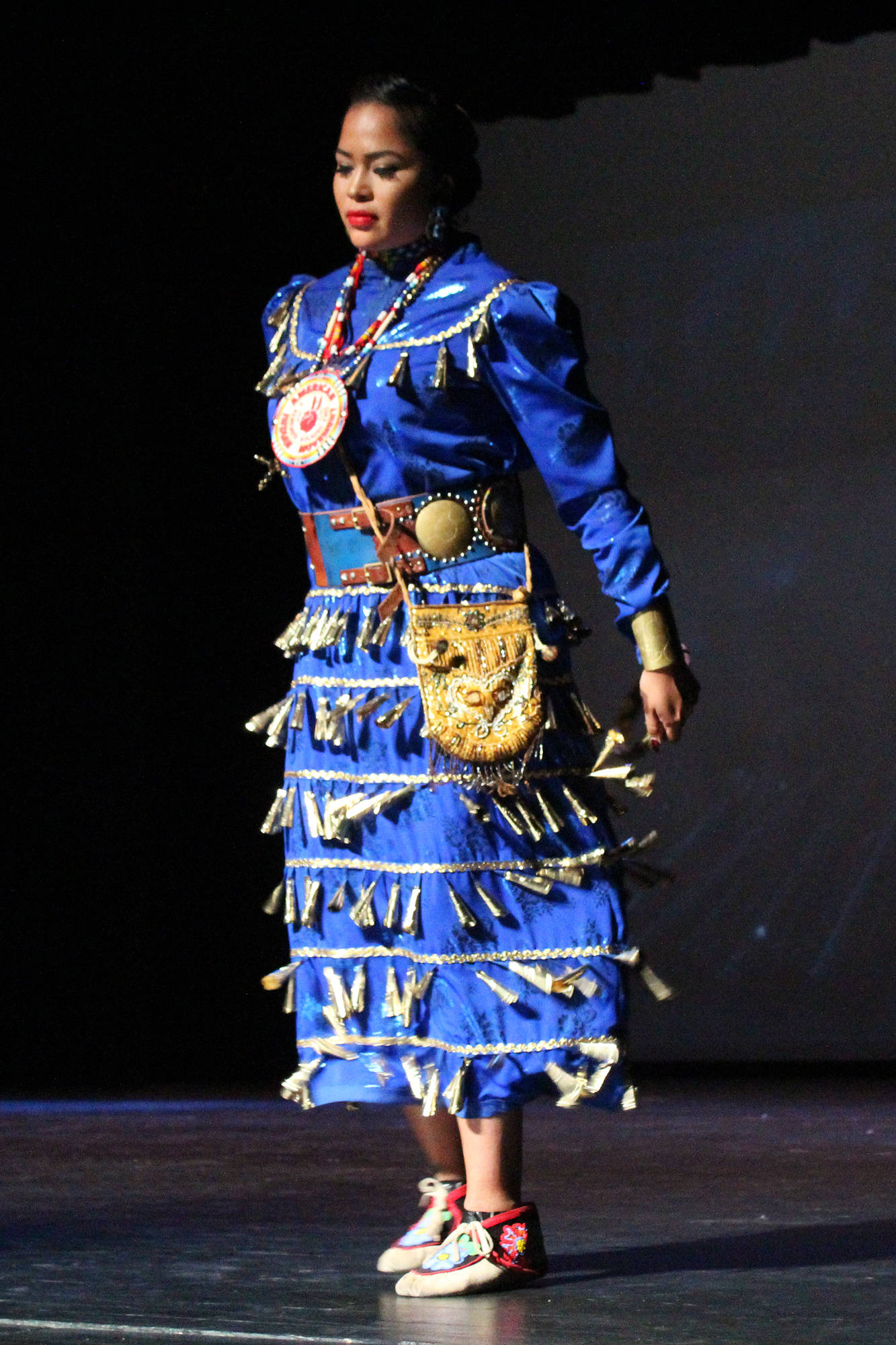 Sheena Cain performs the Anishinaabe side step in what’s called a Jingle Dress on Thursday, Sept. 6, 2018 in the Homer High School Mariner Theatre in Homer, Alaska. She is part of the group Native Pride Dancers that traveled from Minnesota for several performances on the Kenai Peninsula. (Photo by Megan Pacer/Homer News)