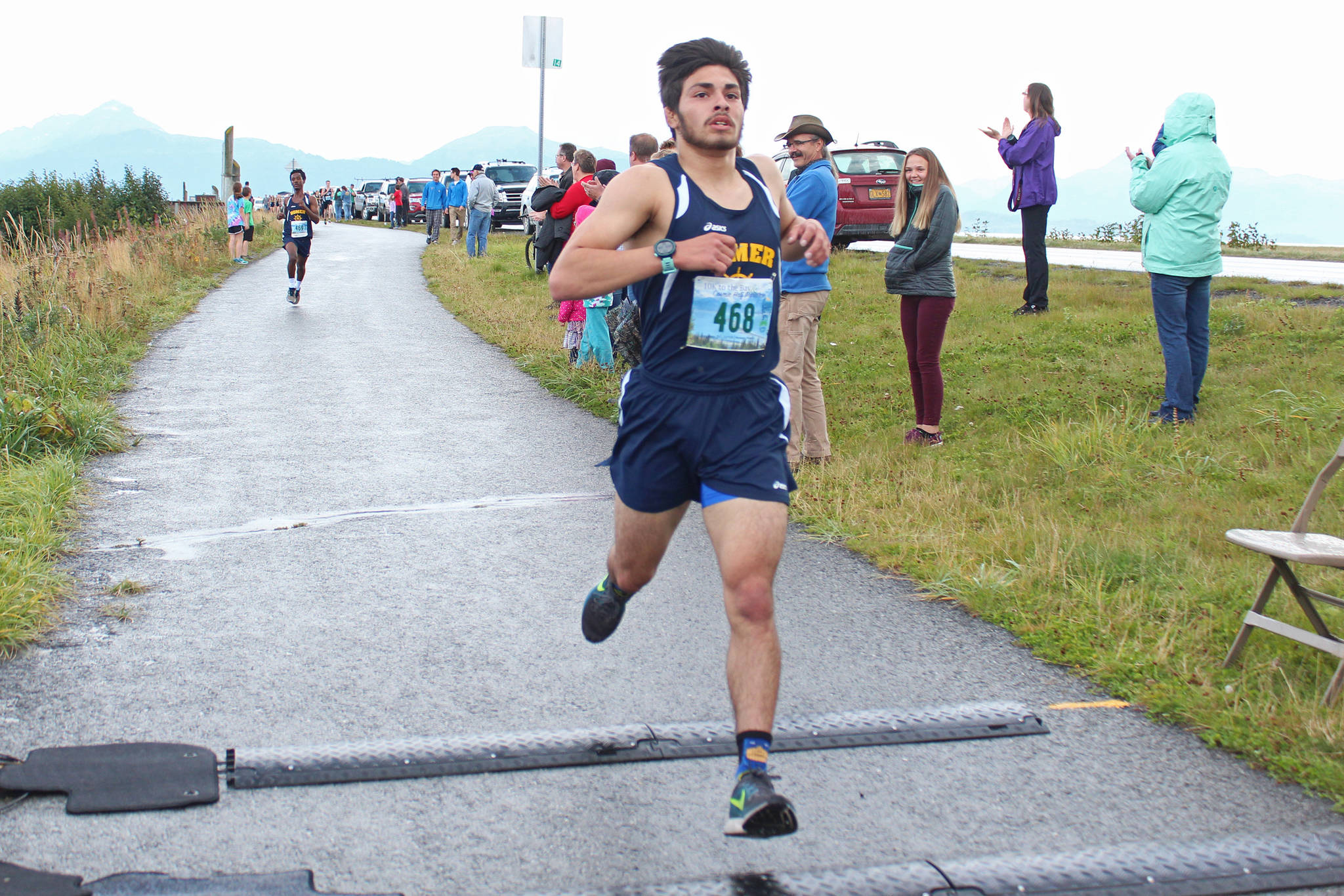 Homer senior Luciano Fasulo crosses the finish line of the 5K men’s Spit Run tot take first place in the cross-country Homer Invitational on Sept. 7, 2018 on the Homer Spit in Homer, Alaska. (Photo by Megan Pacer/Homer News)