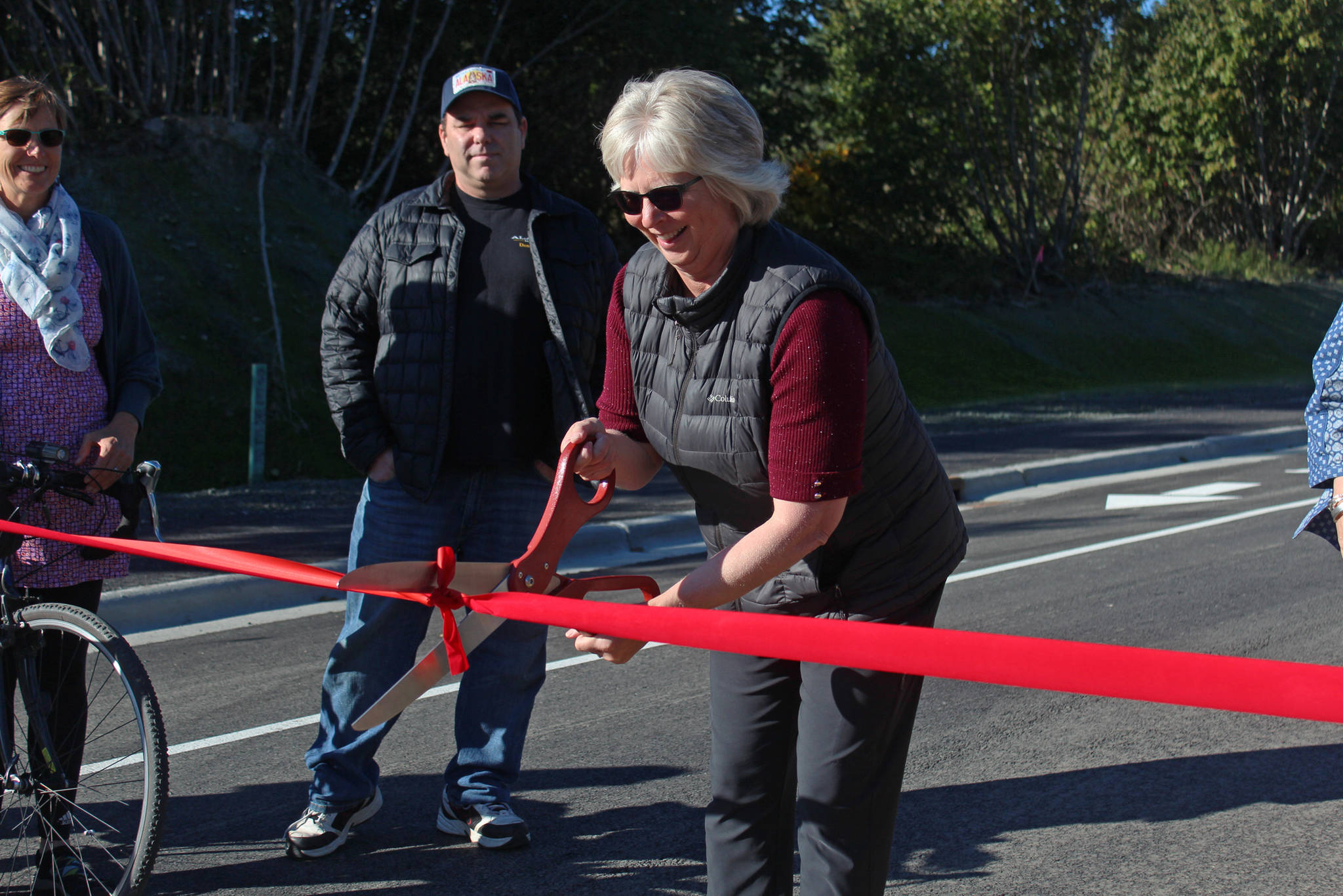 Homer City Council member Shelly Erickson cuts a celebratory ribbon at the grand opening for the Greatland Street expansion Tuesday, Sept. 25, 2018 in Homer, Alaska. Erickson played a large role in getting the project off the ground. (Photo by Megan Pacer/Homer News)