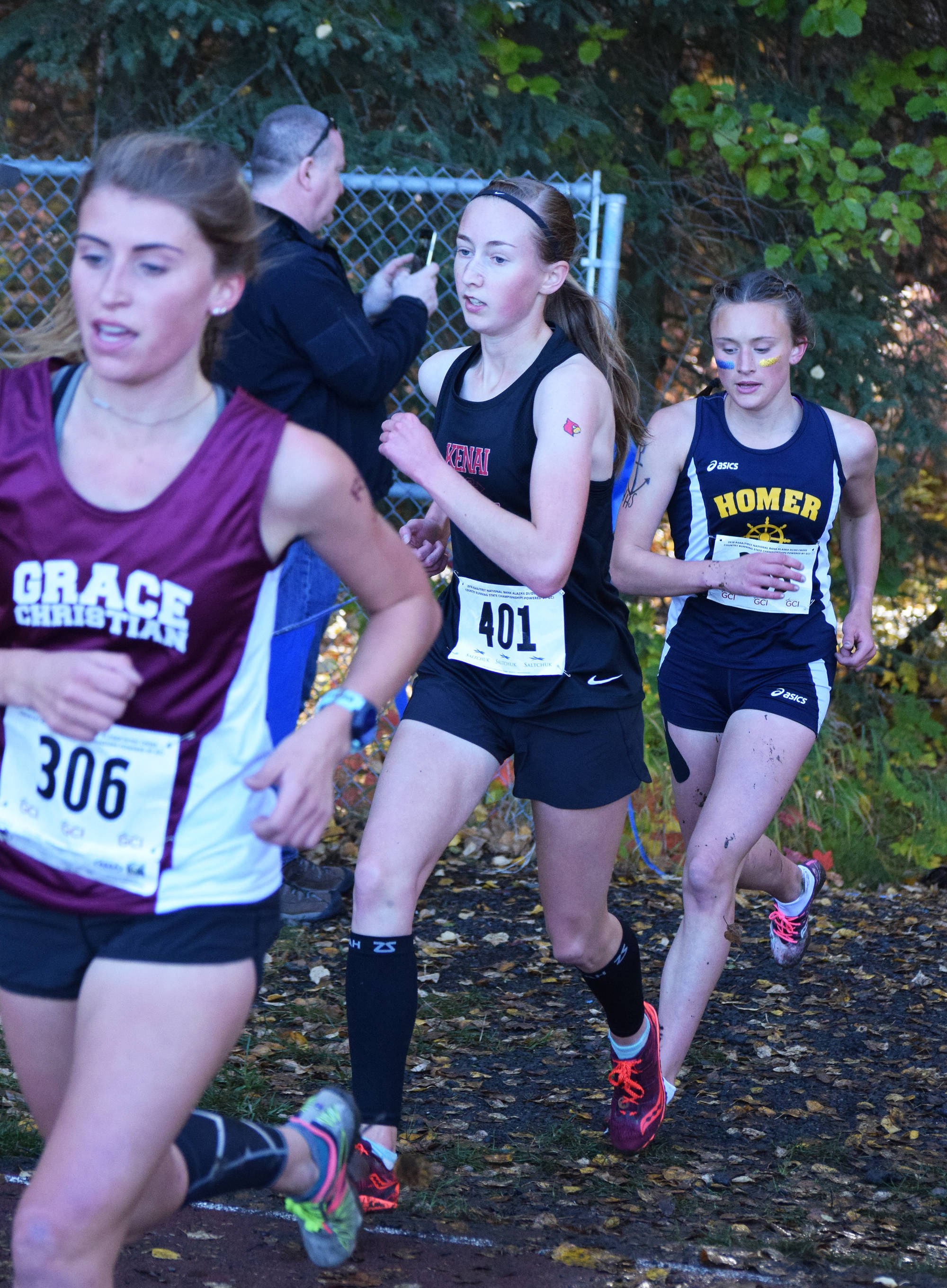 Grace Christian’s Mazzy Jackson (306), Kenai Central senior Jaycie Calvert (401) and Homer junior Autumn Daigle (right) run with the lead pack Saturday in the girls Division II race at the ASAA state cross-country running championships at the Bartlett Trails in Anchorage. (Photo by Joey Klecka/Peninsula Clarion)