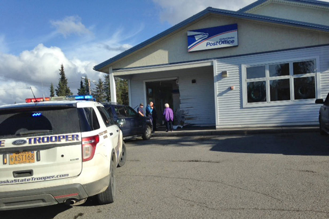 Troopers and others stand near the spot where a black SUV crashed into the front of the Anchor Point Post Office on Friday, Oct. 5, 2018 in Anchor Point, Alaska. In this photo, the vehicle has been moved out of the building, leaving behind a large hole in the front of the post office. (Photo by Yvonne Prucha)