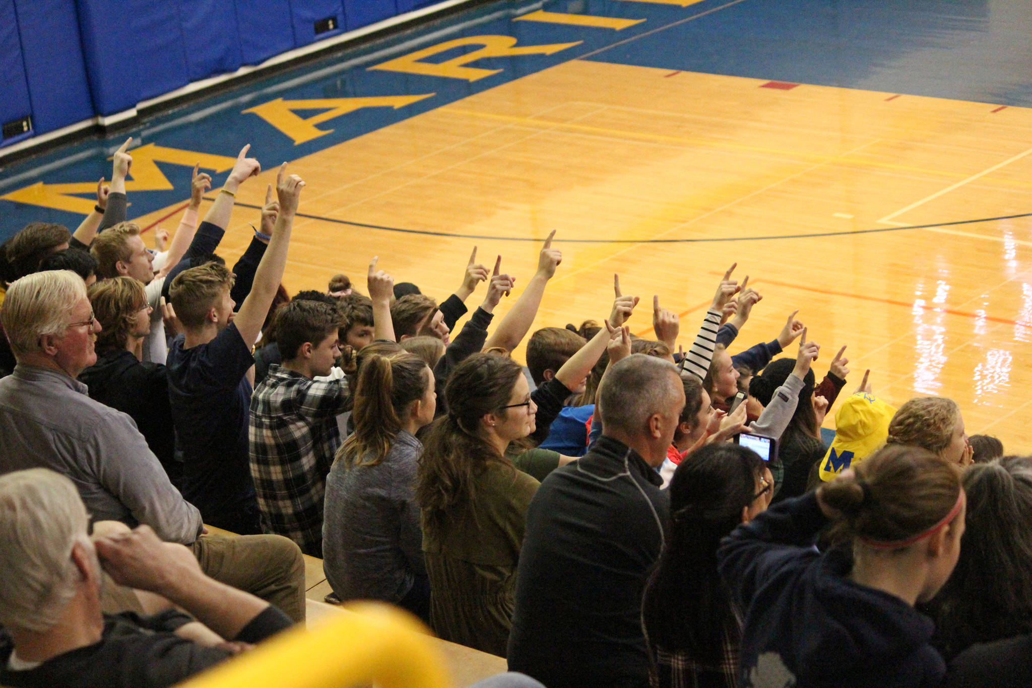 Spectators at the volleyball game between Homer High School and Nikiski on Saturday, Oct. 13, 2018 in Homer, Alaska, hold up one finger to signal that their team had one more point to go in order to win the set. Homer beat Nikiski three games to one. (Photo by Megan Pacer/Homer News)