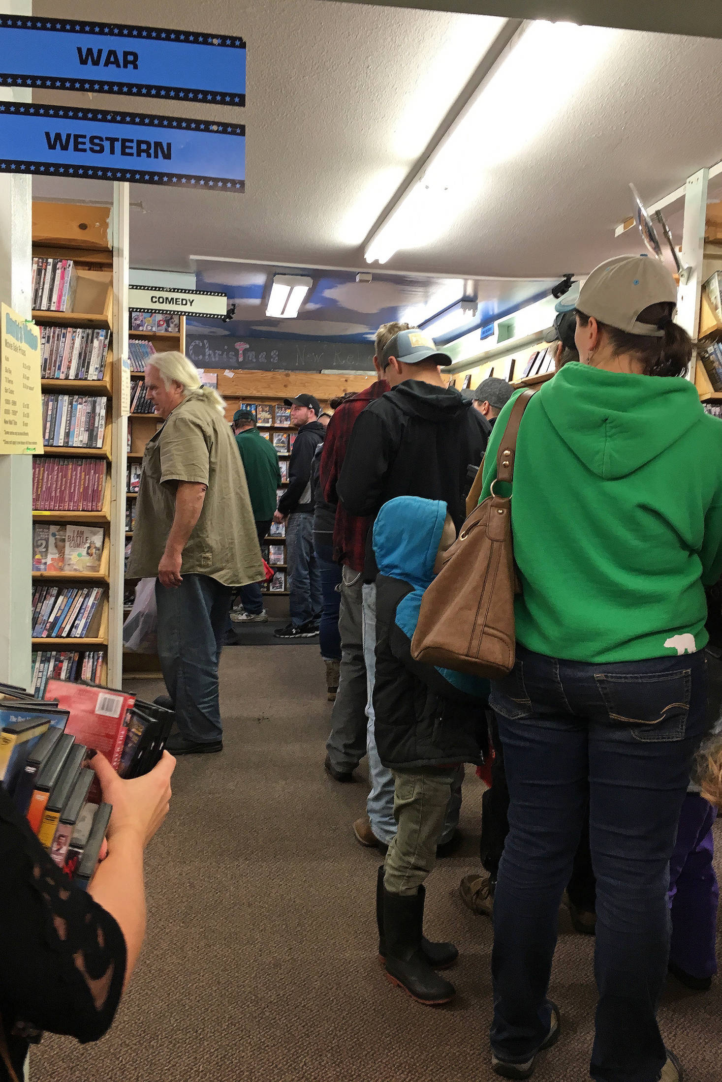 Customers form a line stretching from the register to the back of Barb’s Video and DVD on Saturday, Oct. 20, 2018 in Homer, Alaska during the movie rental store’s first day of its merchandise sale. (Photo by Megan Pacer/Homer News)