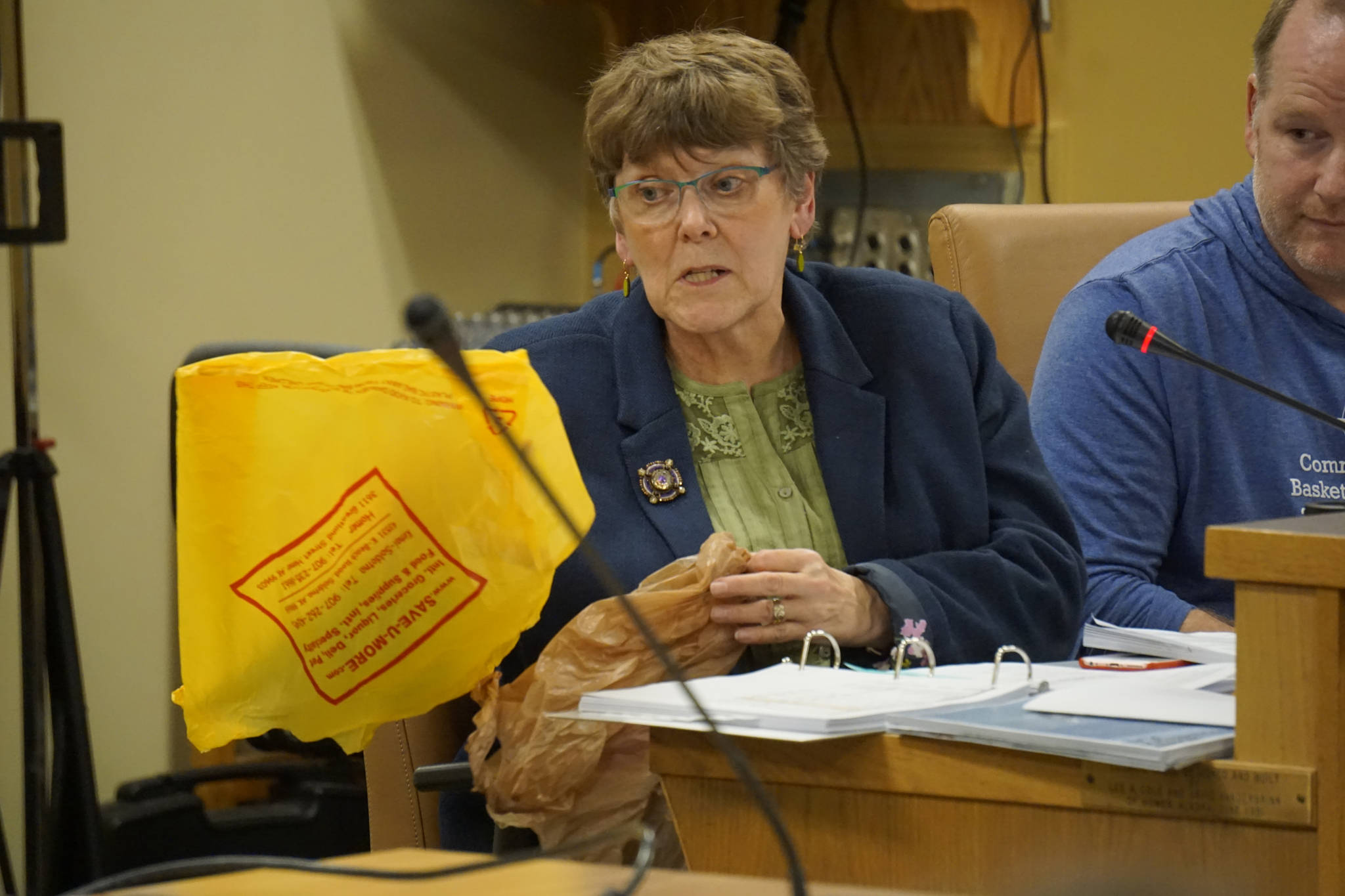 Homer City Council member Caroline Venuti compares a thicker plastic shopping bag, left, with a thinner, single-use plastic shopping bag, right, during an ordinance on a proposal to ban single-use plastic bags in Homer. The council approved an ordinance putting the question to the voters at the October 2019 city election. (Photo by Michael Armstrong/Homer News)