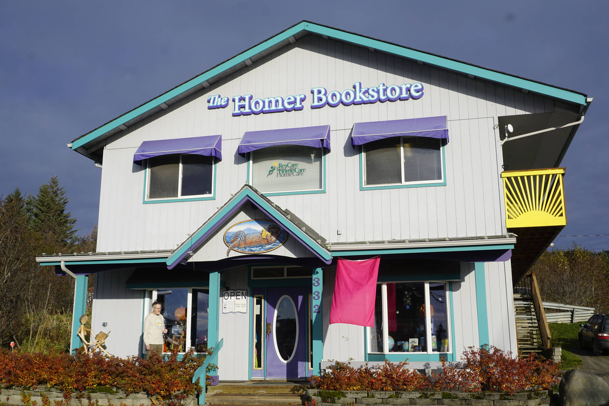 Homer Bookstore co-owner Lee Post stands on the porch of the store at the corner of Pioneer Avenue and Svedlund Street on Oct. 29, 2018, in Homer, Alaska. The upstairs of the building includes offices and apartments for rent. (Photo by Michael Armstrong/Homer News)