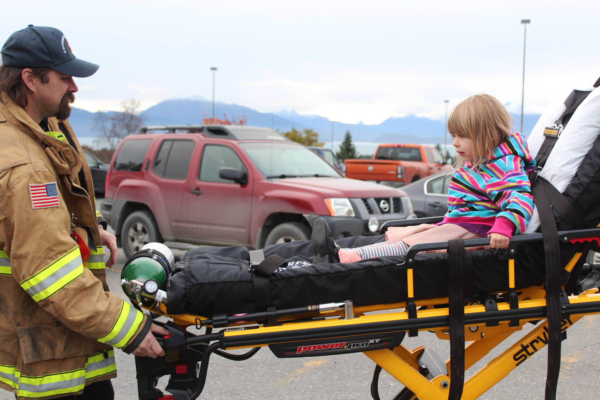 Three-year-old Lenore Jones experiences what a ride on a stretcher is like, courtesy of Jason Miller of Kachemak Emergency Services, during the annual Rotary Health Fair on Saturday, Nov. 3, 2018 held at Homer High School in Homer, Alaska. (Photo by Megan Pacer/Homer News)