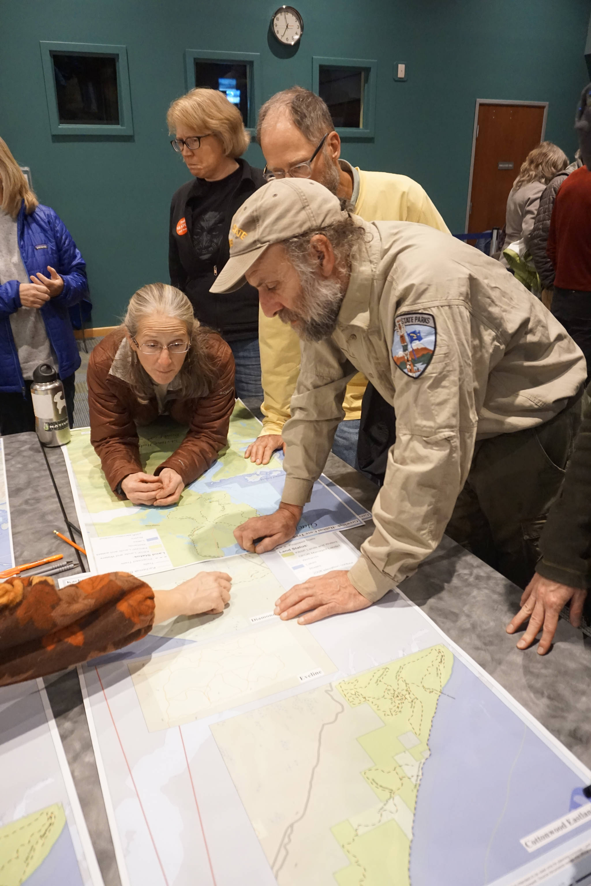 Jennifer Edwards, left, and Alaska State Parks specialist Eric Clarke, right, discuss the Diamond Creek trails portion of the Kachemak Bay State Park and State Wilderness Park draft management plan at an open house on the plan on Oct. 29, 2018, at the Alaska Islands and Ocean Visitor Center in Homer, Alaska. (Photo by Michael Armstrong/Homer News)