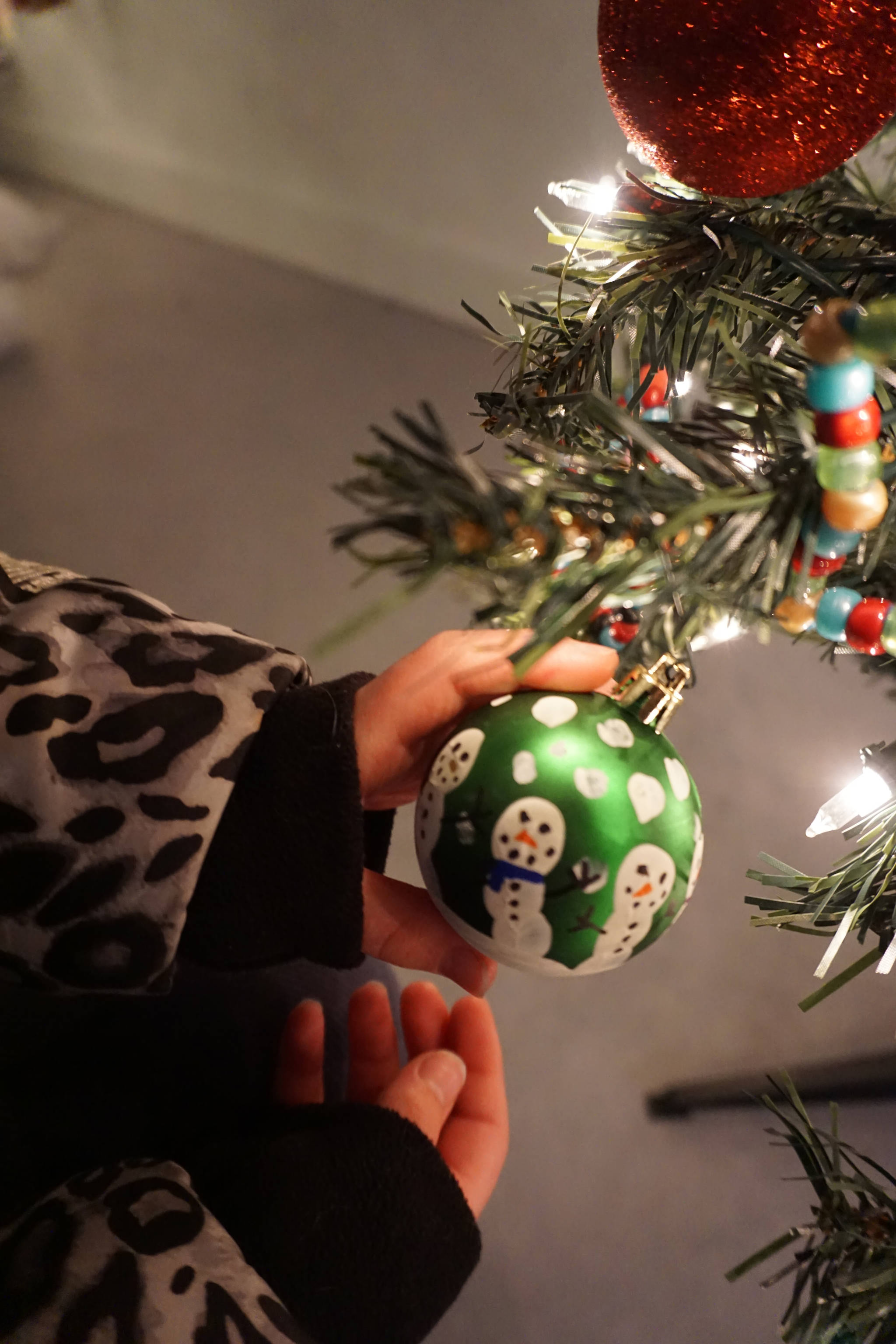 Pinky Sarber holds an ornament she made for a Christmas tree decorated by Paul Banks Elementary School students for a fundraiser Friday, Dec. 1, 2017 in Homer, Alaska benefitting South Peninsula Haven House. Young artists made the snowmen by tracing their fingers. Local nonprofits decorated trees that were auctioned off in a silent auction at a space Haven House uses for special events on Bunnell Avenue in Homer. (Photo by Michael Armstrong, Homer News)