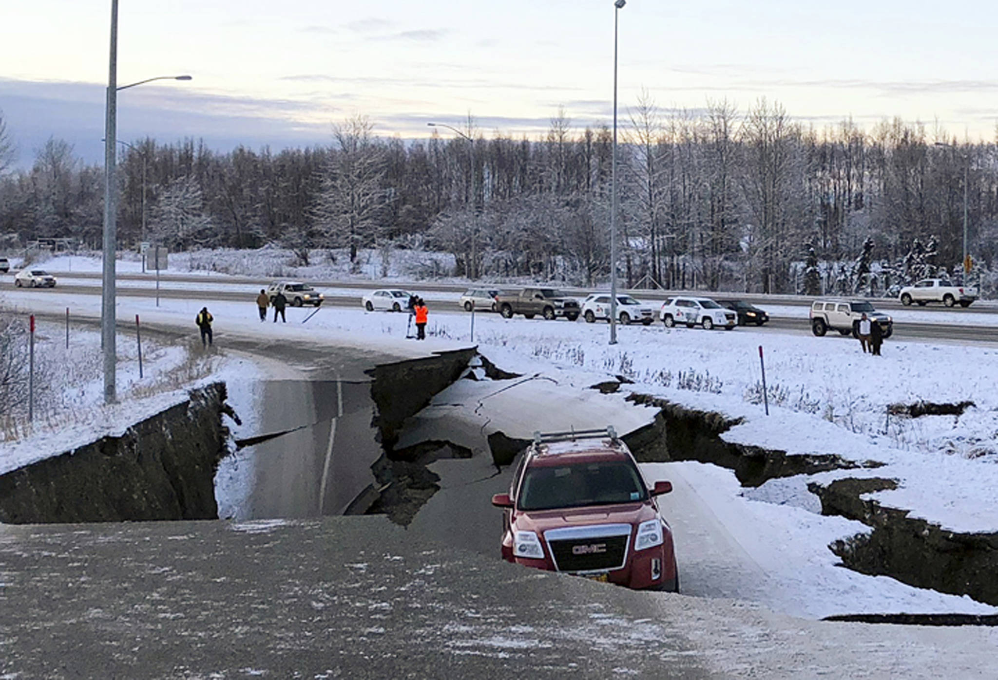 FILE - In this Friday, Nov. 30, 2018 file photo, Tom Sulcynski’s vehicle is trapped on a section of road that collapsed during an earthquake in Anchorage, Alaska. The collapsed roadway that became an iconic image of the destructive force of a magnitude 7.0 earthquake and its aftershocks was repaired just days after the quake. The off-ramp connecting Minnesota Drive and a road to Ted Stevens Anchorage International Airport reopened Tuesday, Dec. 4, 2018, with shoulder work finished Wednesday. (AP Photo/Dan Joling, File )