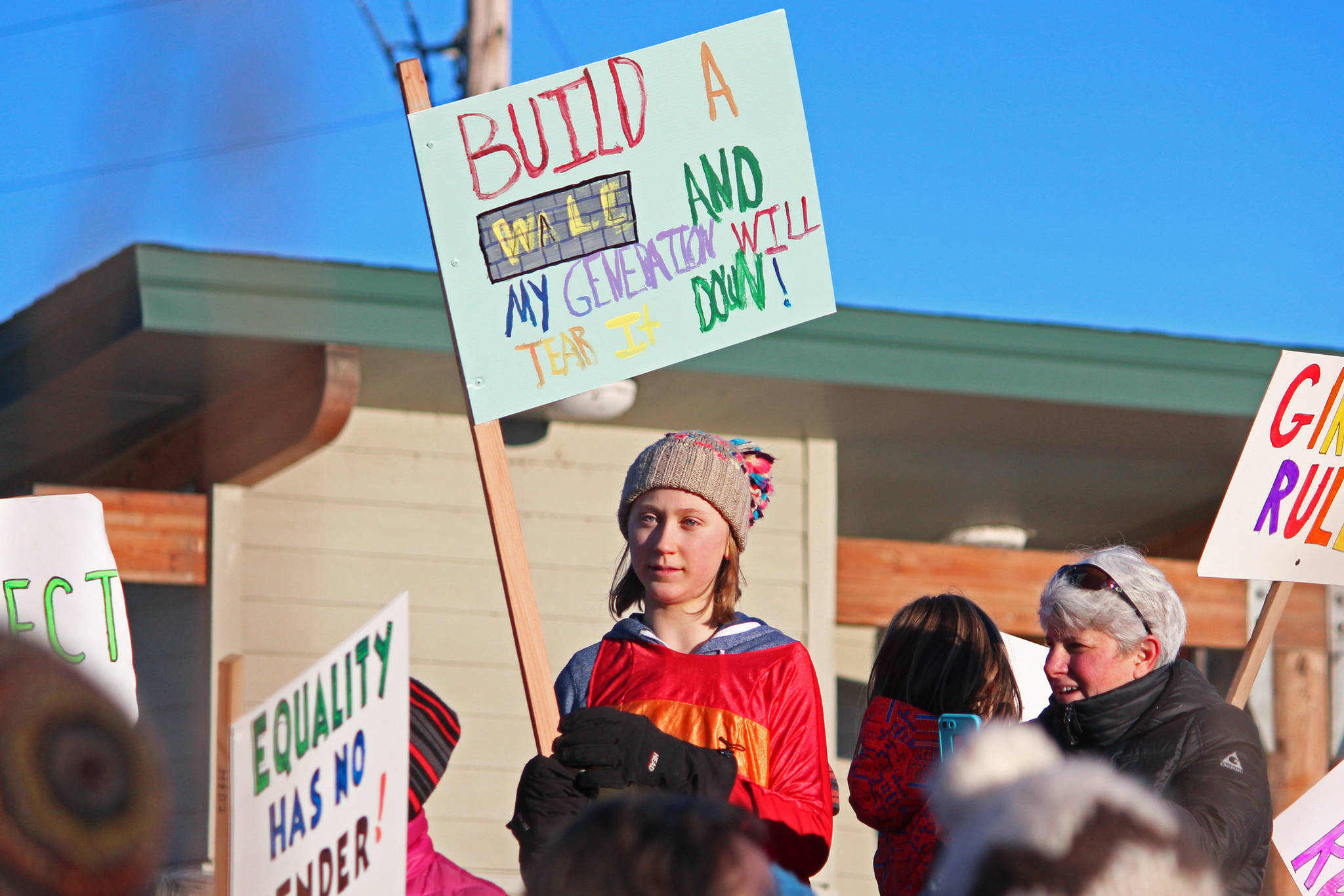A girl holds up a sign reading, “Build a wall and my generation will tear it down,” at WKFL Park following the 2019 Women’s March on Homer on Saturday, Jan. 19, 2019 in Homer, Alaska. (Photo by Megan Pacer/Homer News)