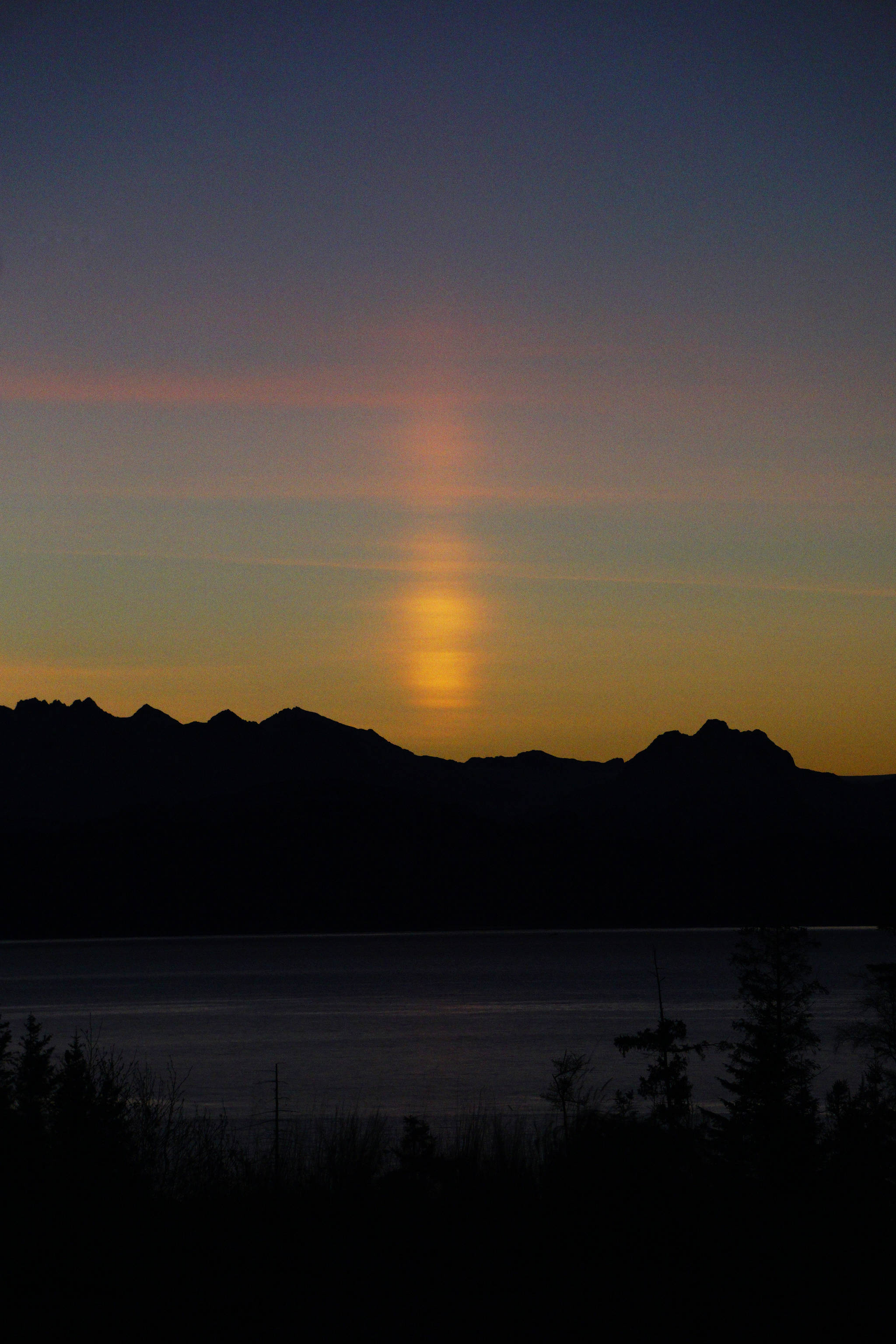 A sun pillar appears over the Kenai Mountains at sunrise about 9:20 a.m. Friday, Jan. 18, 2019, in Homer, Alaska. A sun pillar forms when light from the rising or setting sun is reflected by ice crystals in thin, high-level clouds. (Photo by Michael Armstrong/Homer News)