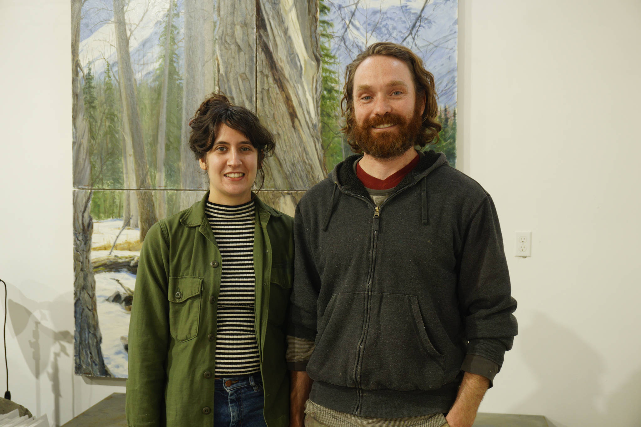 Elissa and David Pettibone pose on Tuesday, Oct. 16, 2018, by one of David Pettibone’s paintings at The Shop, an art space the Pettibones started in August 2018 in Kachemak City, Alaska. (Photo by Michael Armstrong/Homer News)