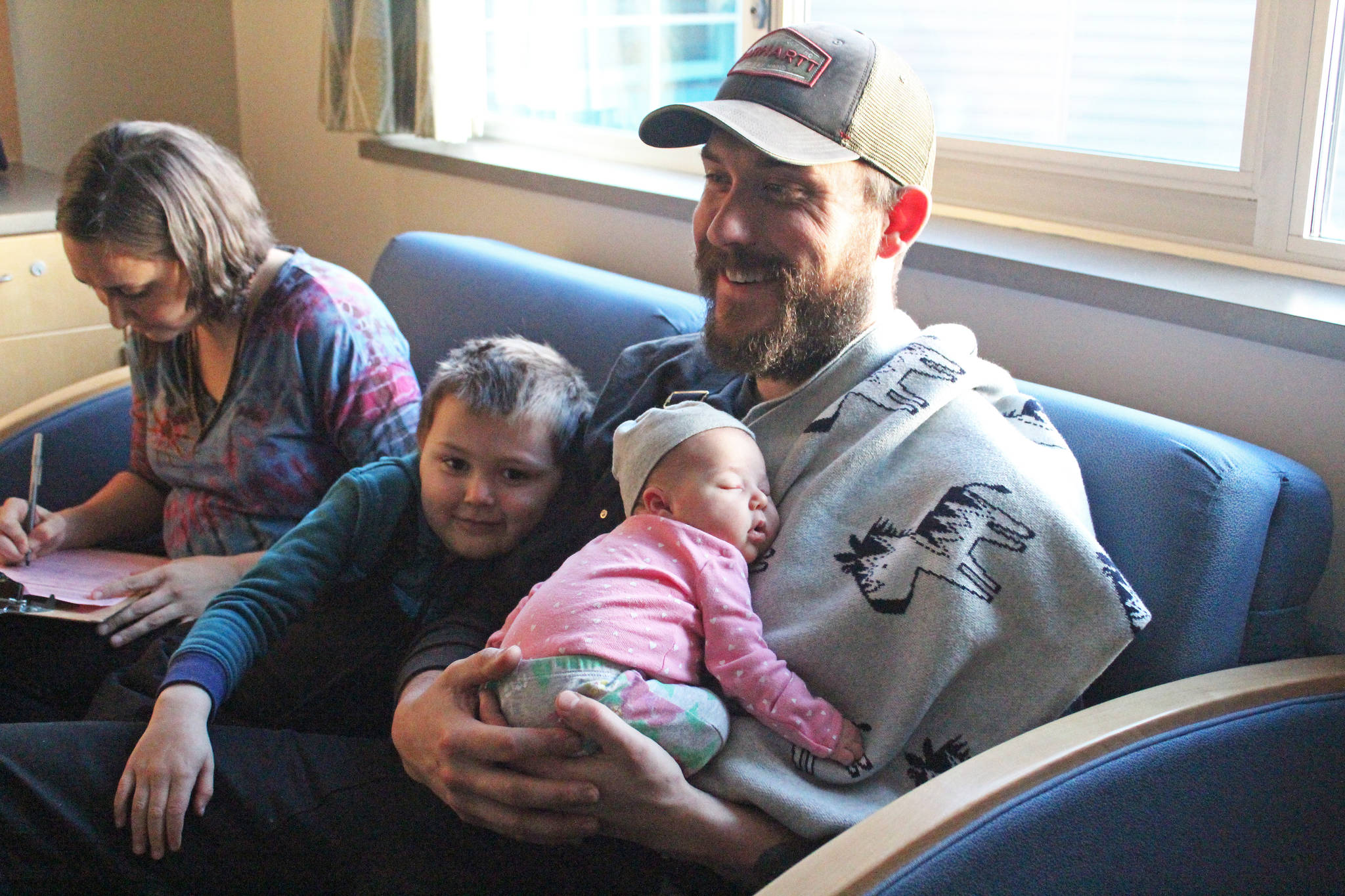 <span class="neFMT neFMT_PhotoCredit">Photo by Megan Pacer/Homer News</span>                                Owen Bettinger and his son, Juneau, relax with new daughter, Sequoia, while his wife, Allyse, fills out some paperwork Tuesday, Jan. 8, 2019 at South Peninsula Hospital in Homer, Alaska. Sequoia was the first baby born in the new year on Jan. 1.