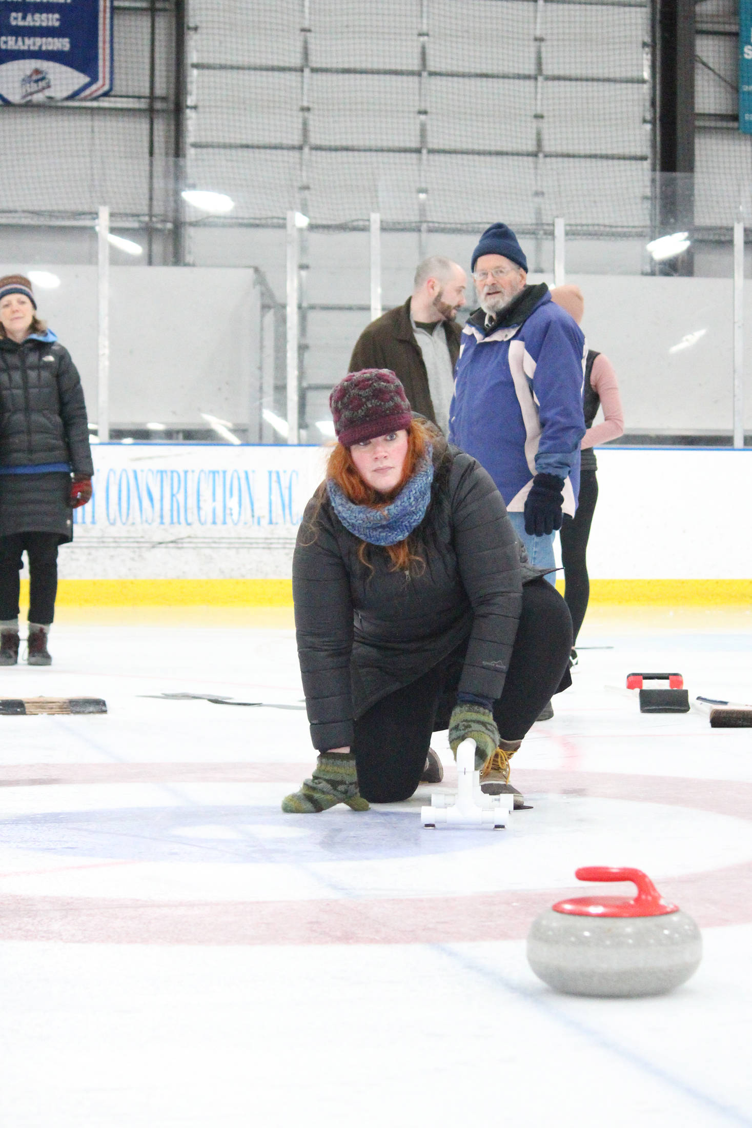 Trina Uvaas watches the progress of a curling stone she practiced delivering during a Learn to Curl fundraising event Saturday, Jan. 12, 2019 at the Kevin Bell Arena in Homer, Alaska. (Photo by Megan Pacer/Homer News)