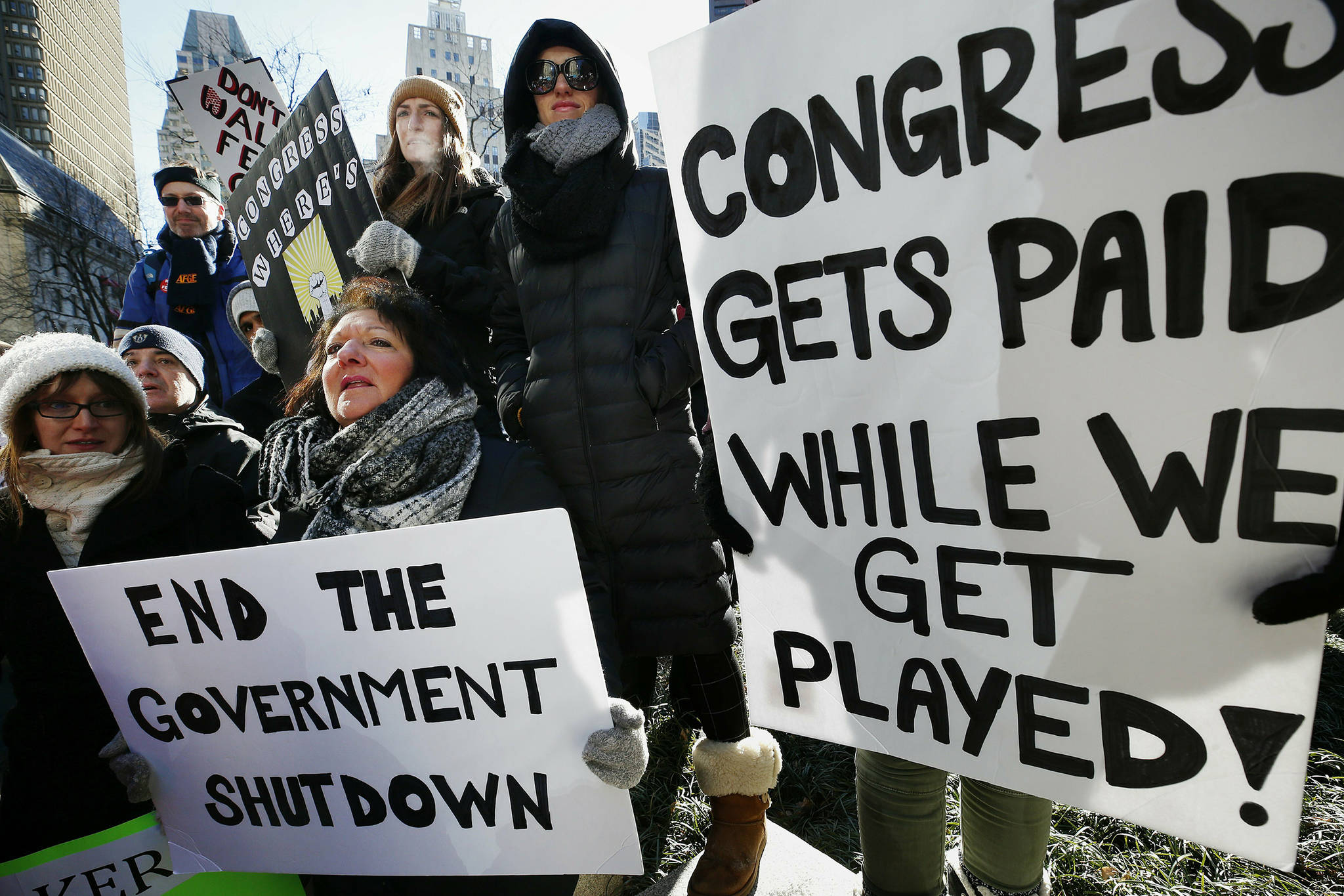 Government workers and their supporters hold signs during a protest in Boston, Friday, Jan.11, 2019. The workers rallied with Democratic U.S. Sen. Ed Markey and other supporters to urge that the Republican president put an end to the shutdown so they can get back to work. (AP Photo/Michael Dwyer)