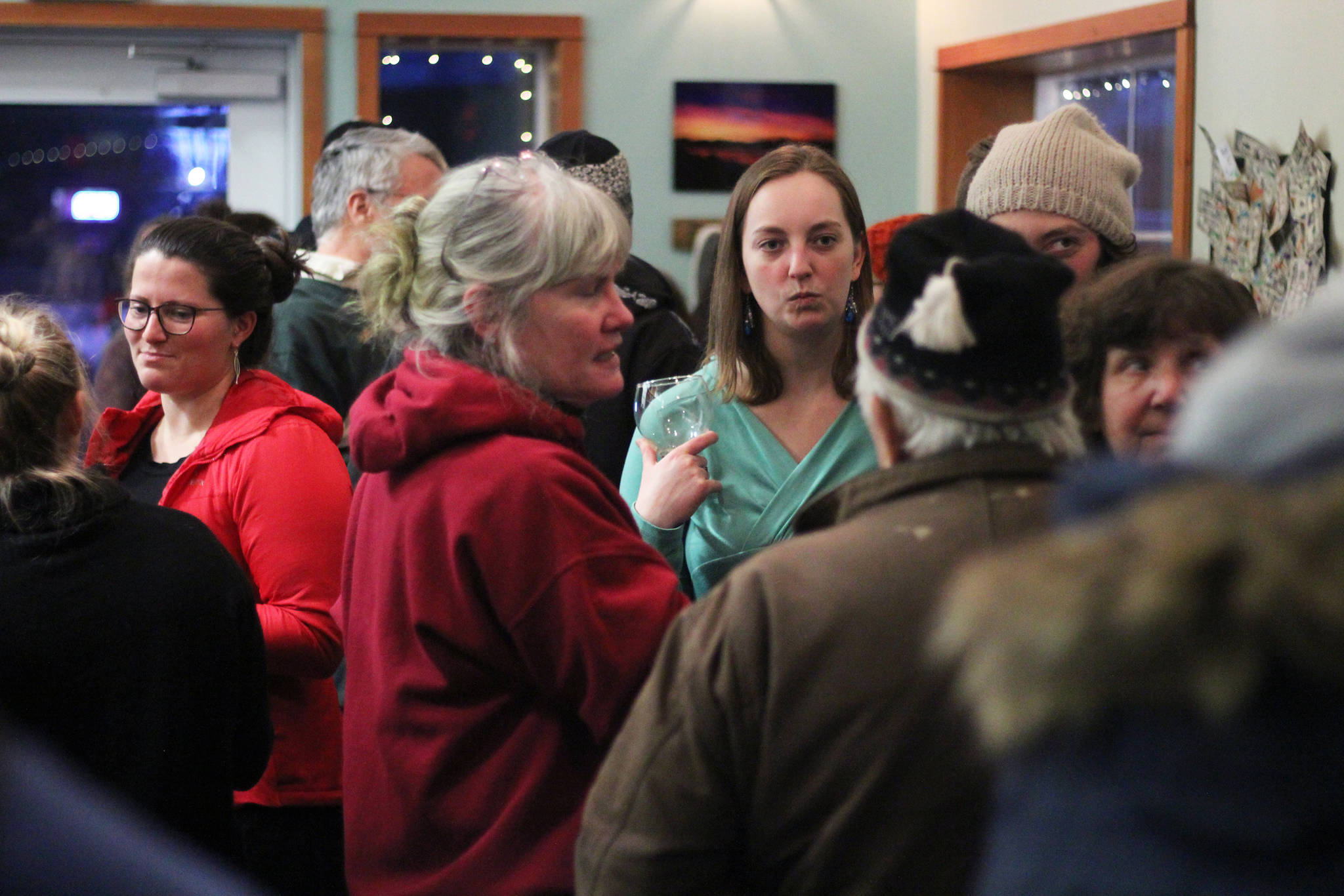 A crowd of people talks and mingles at the First Friday opening Friday, Feb. 1, 2019 at Grace Ridge Brewery in Homer, Alaska. The winning label for a special Brackish Brown ale was unveiled at the event. (Photo by Megan Pacer/Homer News)