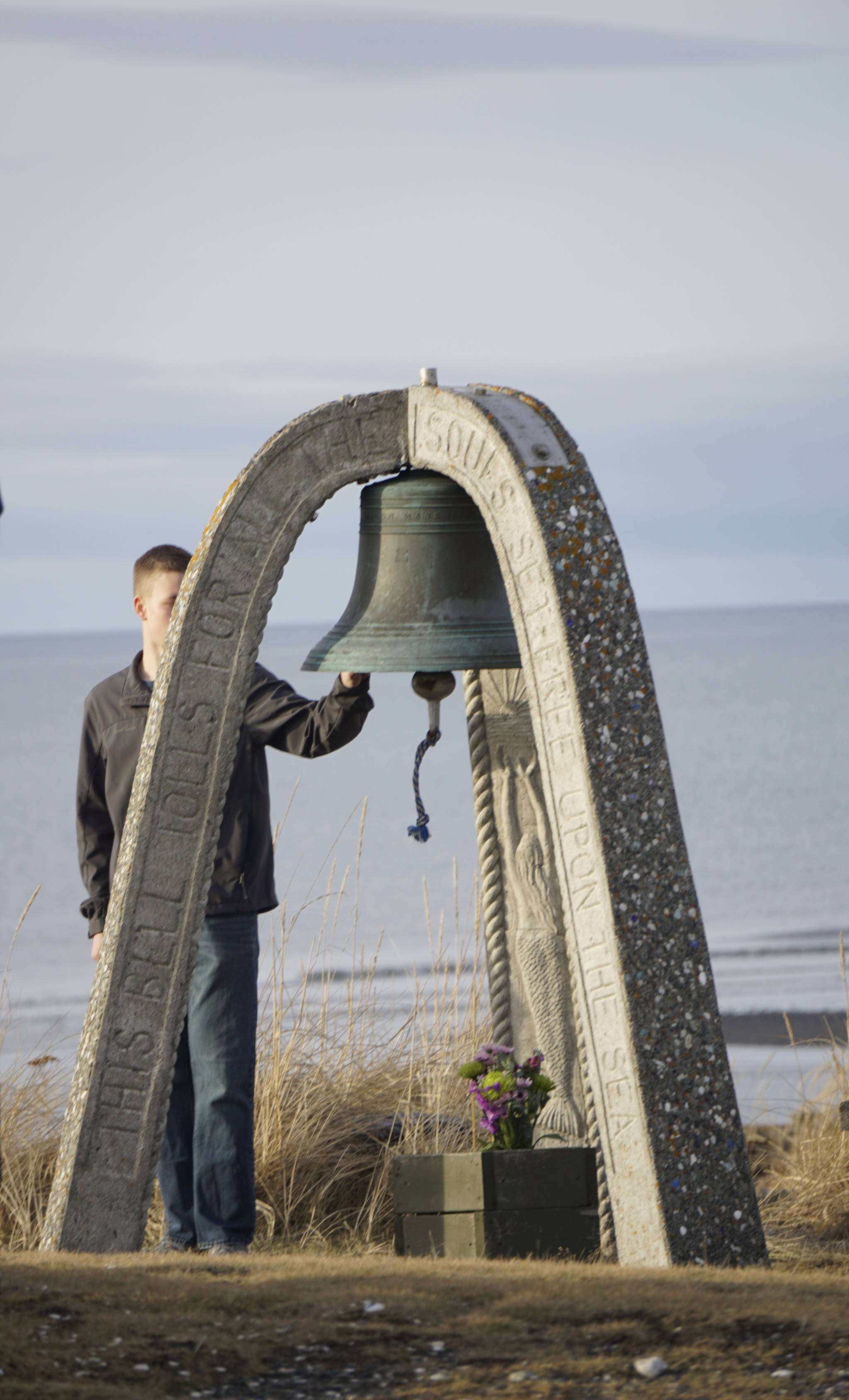 Seaman James Cloutier of the U.S. Coast Guard Cutter Hickory rings the end-of-watch bell for Chief Warrant Officer Michael Kozloski at a memorial service for him on Friday morning, Feb. 8, 2019, at the Seafarer’s Memorial on the Homer Spit, Homer, Alaska. (Photo by Michael Armstrong/Homer News)