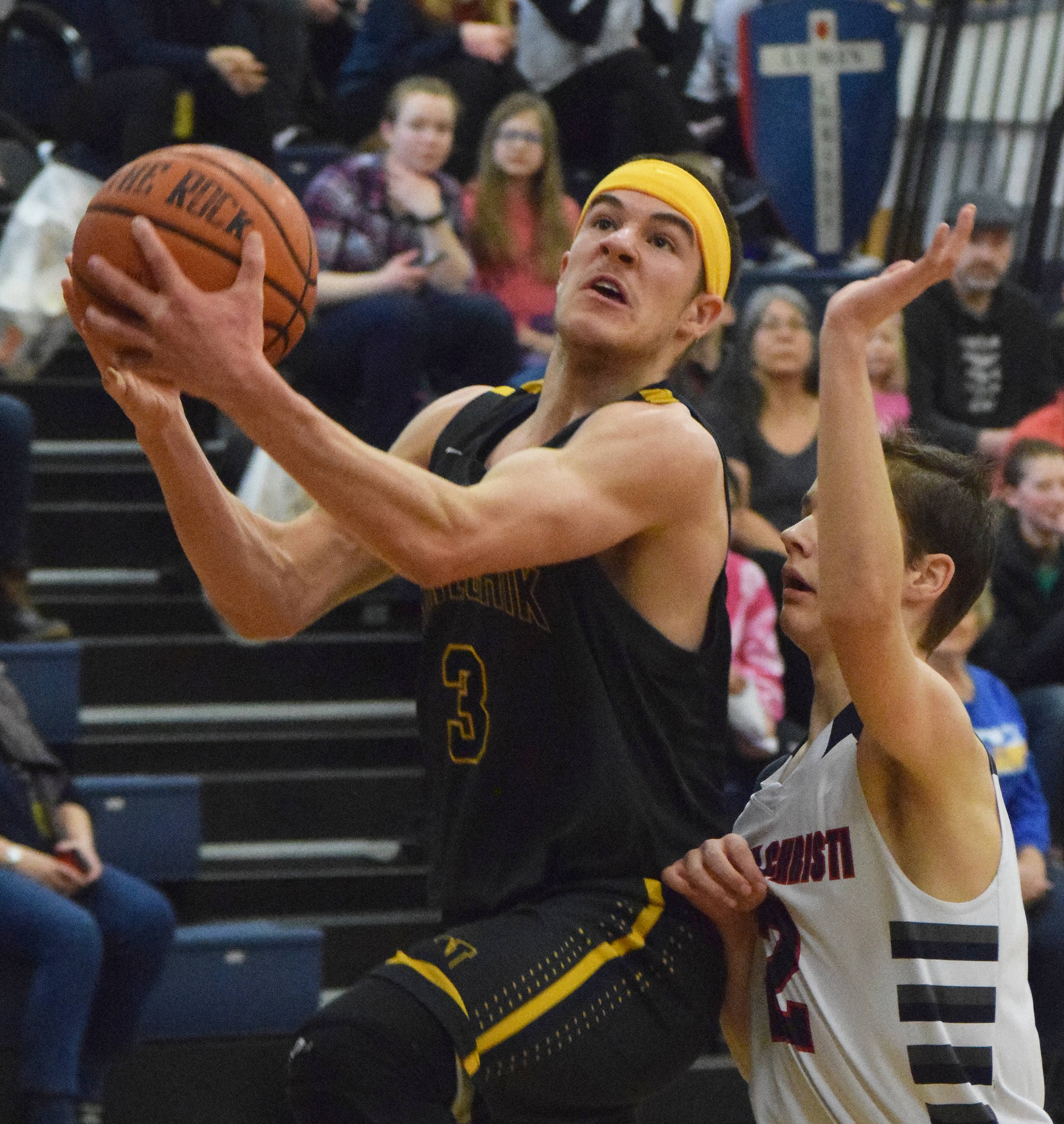 Ninilchik’s Garrett Koch (left) drives to the rim against Lumen Christi defender Brendon Gregory Saturday in the boys Peninsula Conference second-place contest. (Photo by Joey Klecka/Peninsula Clarion)