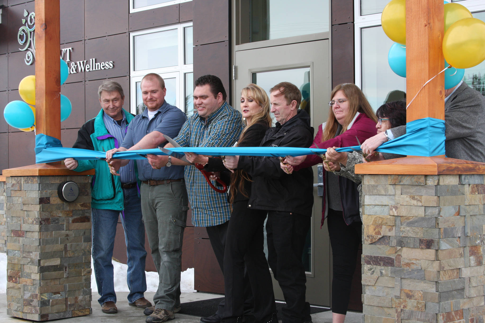 From left to right, John Baker, Jacob Baker, Paul Baril, Crystal Collier, Kim Collier, Trinket Gallien, Lillian Elvsaas, and John Crawford prepare to cut the ribbon for the new Anchor Point SVT Health and Wellness Center at the grand opening ceremony at noon Friday, March 8, 2019, in Anchor Point, Alaska. (Photo by Delcenia Cosman)