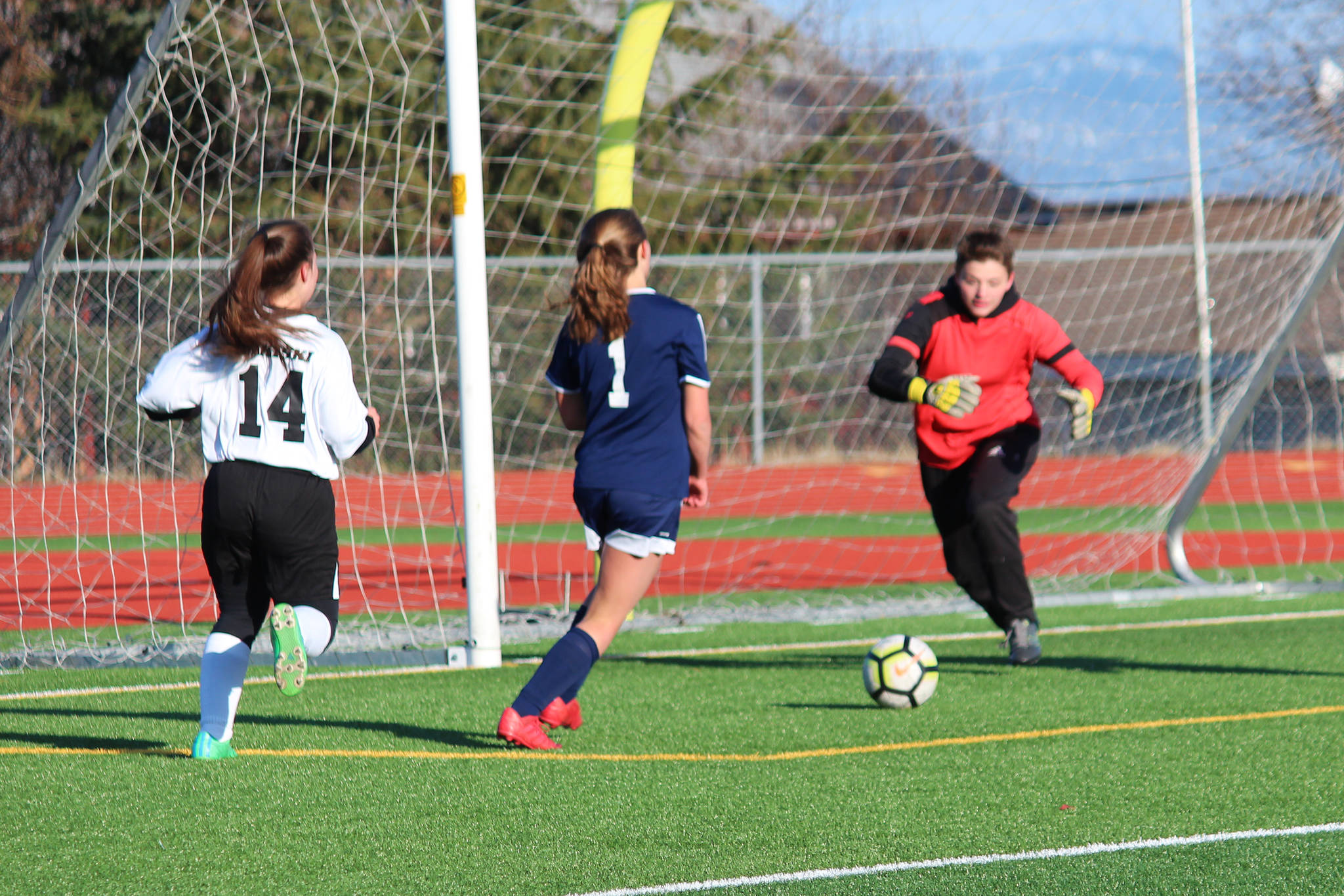 Nikiski’s Abby Bystedt rushes to a ball shot by Homer’s Aiyana Cline (center) during a Tuesday, April 23, 2019 game at Homer High School in Homer, Alaska. (Photo by Megan Pacer/Homer News)
