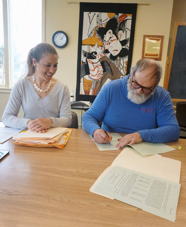 Homer City Manager Katie Koester, left, watches Homer Mayor Ken Castner sign a $4.1 million bond to fund construction of the new Homer Police Station at Homer City Hall on April 24, 2019, in Homer, Alaska. (Photo provided)