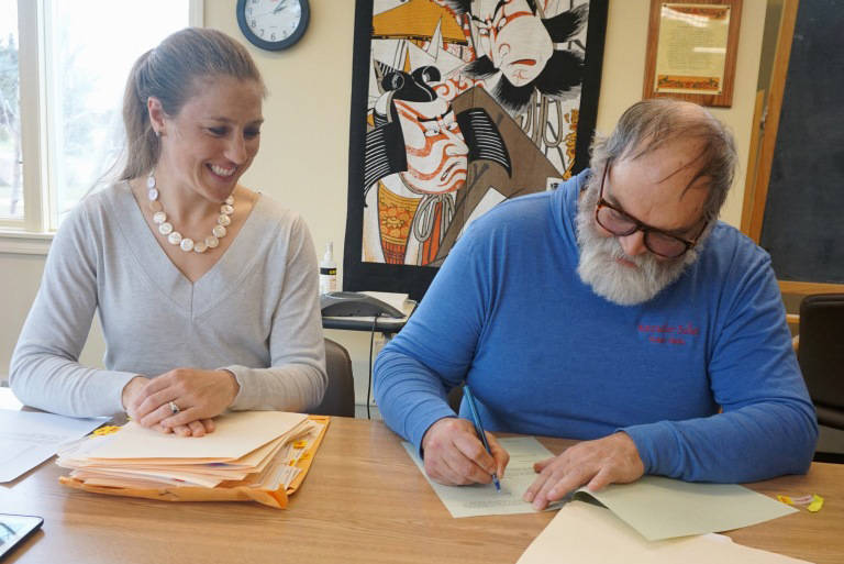 Homer City Manager Katie Koester, left, watches Homer Mayor Ken Castner sign a $4.1 million bond to fund construction of the new Homer Police Station at Homer City Hall on April 24, 2019, in Homer, Alaska. (Photo provided)