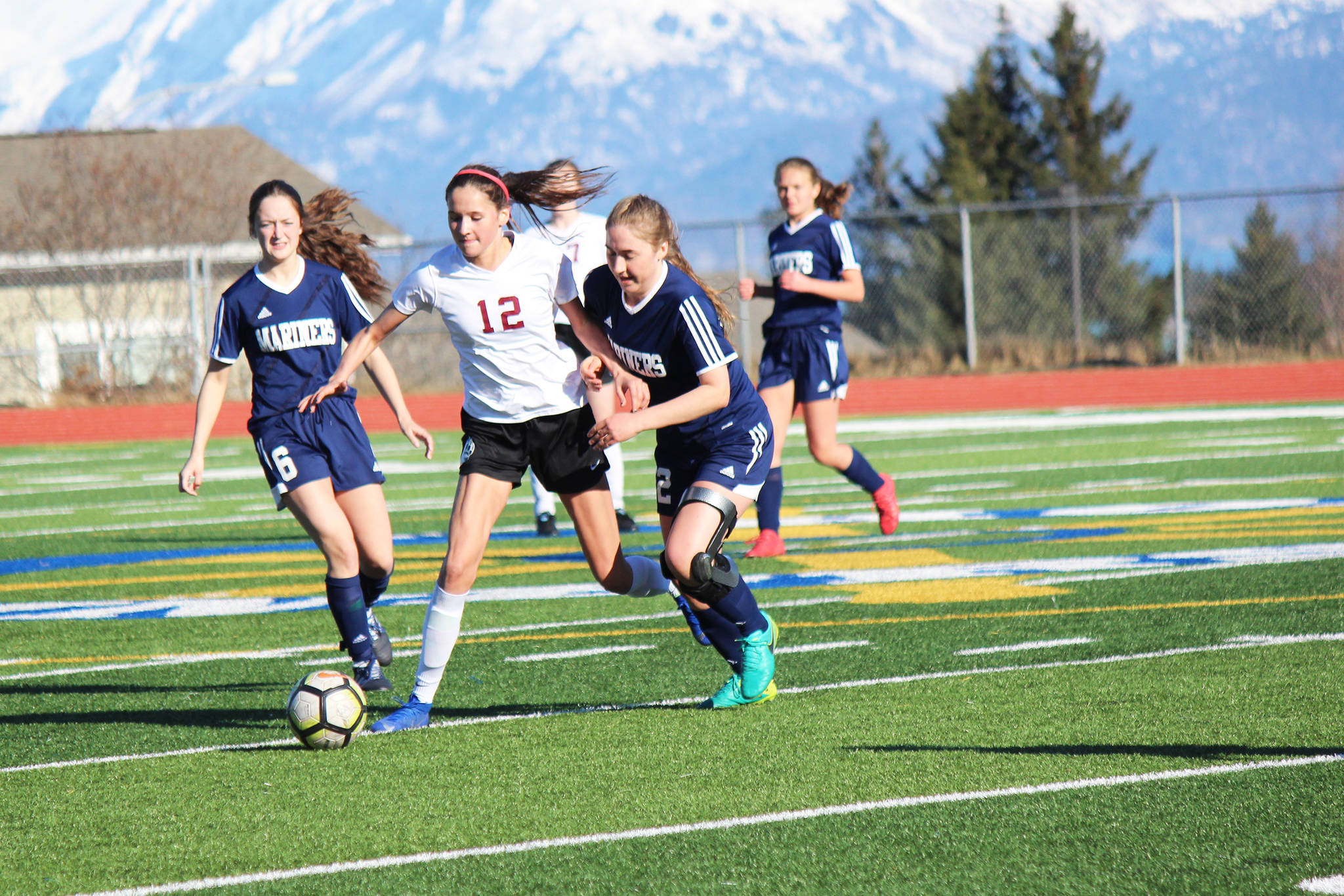 Mariners Eve Brau, left, and Brenna McCarron, right, edge a Grace Christian player out of the action during Friday’s varsity soccer game on April 26, 2019, at the high school in Homer, Alaska. (Photo by McKibben Jackinsky).