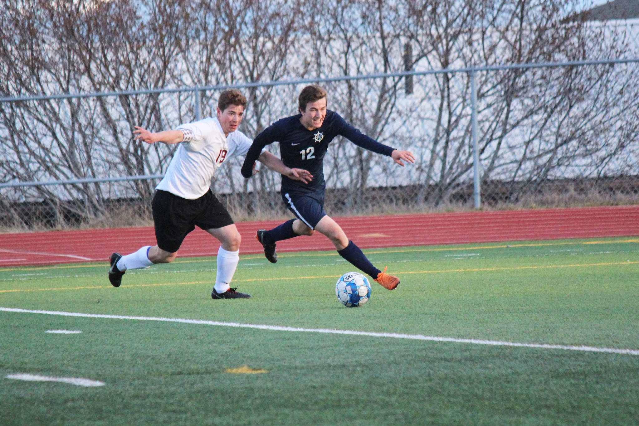 In some one-on-one action at Friday’s varsity soccer game against Grace Christian, on Friday, April 26, 2019, at the high school in Homer, Alaska Mariner Daniel Reutov, 12, sends the ball down the field. (Photo by McKibben Jackinsky)
