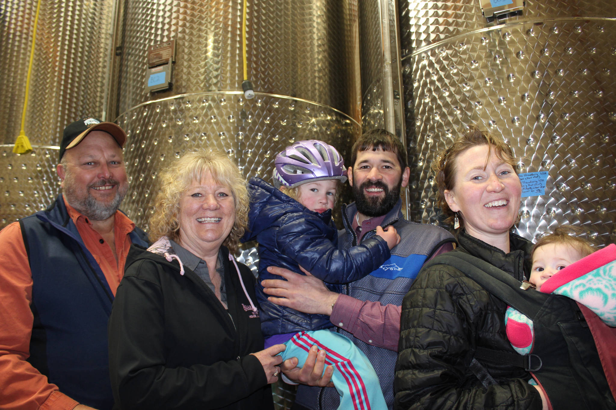 In March, Bear Creek Winery and Lodging founders Bill and Dorothy Fry, left, officially signed the business over to their son-in-law and daughter Louis and Jasmine Maurer, shown here with their two daughters, Maggie, 4, and Aurora, six months. They posed for a photo on April 17, 2019, at the winery in Kachemak City, Alaska. (Photo by McKibben Jackinsky)