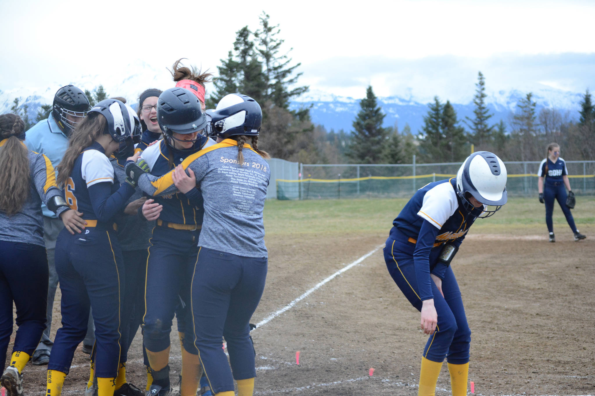 Homer High School Mariners softball batter Grace Godfrey gets a hug from her teammates after she hit a home run on Tuesday, April 30, 2019, against Soldotna High School at Jack Gist Park in Homer, Alaska. (Photo by Michael Armstrong/Homer News)
