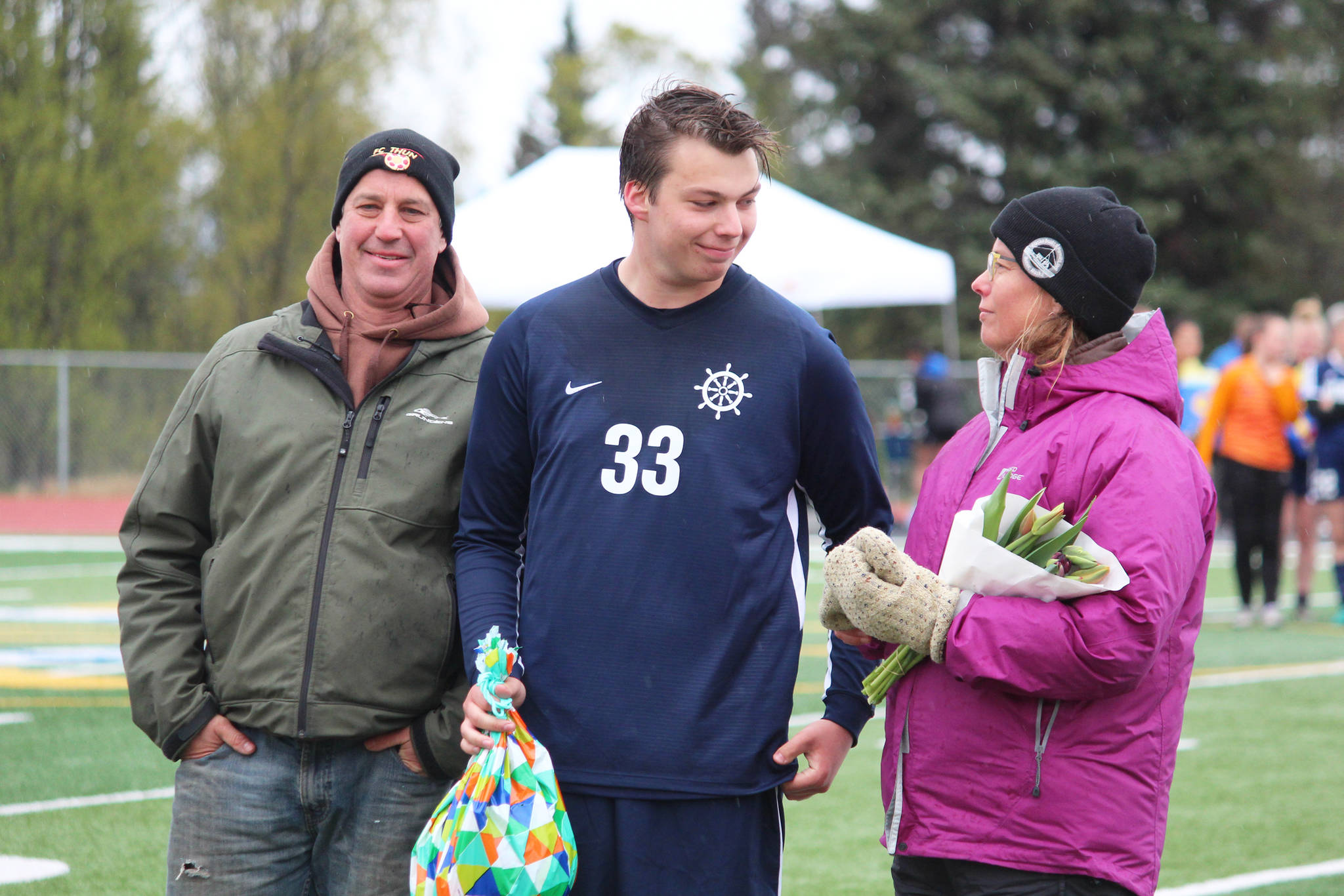 Midfielder Henry Russell celebrates with his parents while being recognized during a Senior Night ceremony between soccer games Friday, May 10, 2019 at Homer High School in Homer, Alaska. (Photo by Megan Pacer/ Homer News)