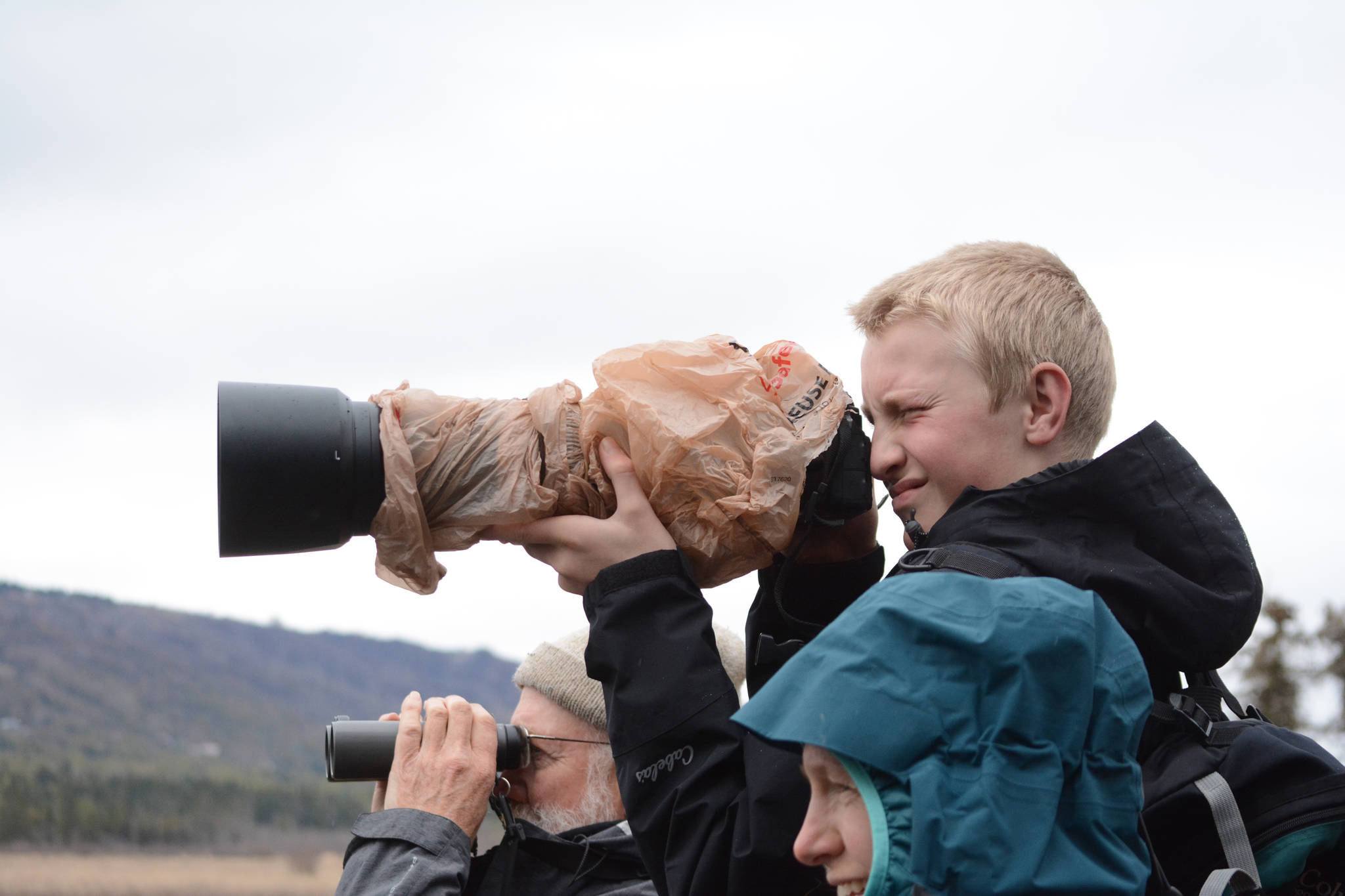Josiah Verbrugge, 14, photographs birds with his mother, Heather Verbrugge, at Beluga Lake on May 10, 2019, in Homer, Alaska, during the Kachemak Bay Shorebird Festival. He rented the big lens just for the festival. (Photo by Michael Armstrong/Homer News)